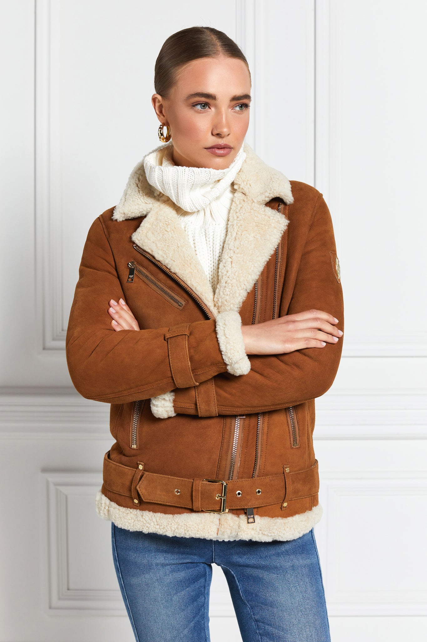 classic aviator jacket in tan leather with cream shearling inside that accents the cuffs hem and collar with belt detail on the hem and cuffs three pockets and angular zip fastening