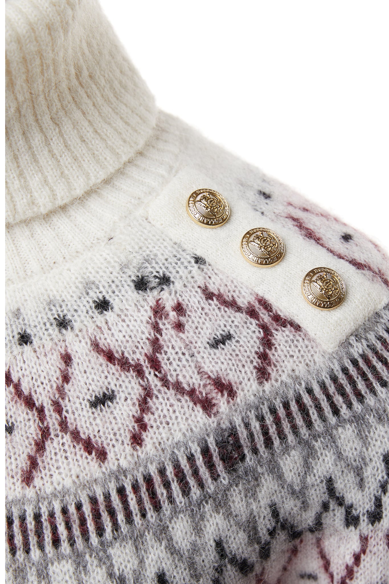 gold button detail across shoulders of a classic cream roll neck jumper with fairisle knit in red and grey around the shoulders waistline and cuffs and a split ribbed hem 