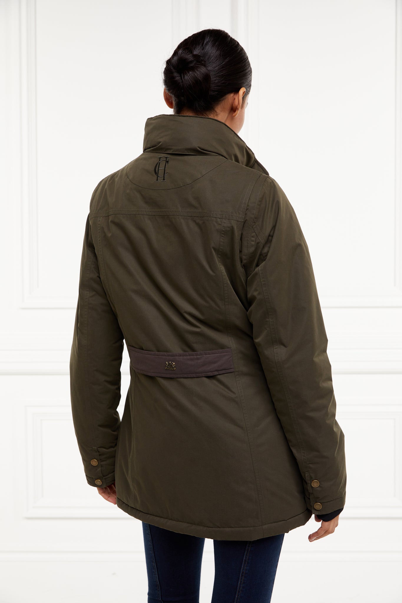 back of multiway coat in khaki that works as a 3 in 1 a waterproof outer coat with stowaway hood and deep pockets and black jersey storm cuffs and a fleece gilet inner with tan leather trims can be worn together or separately