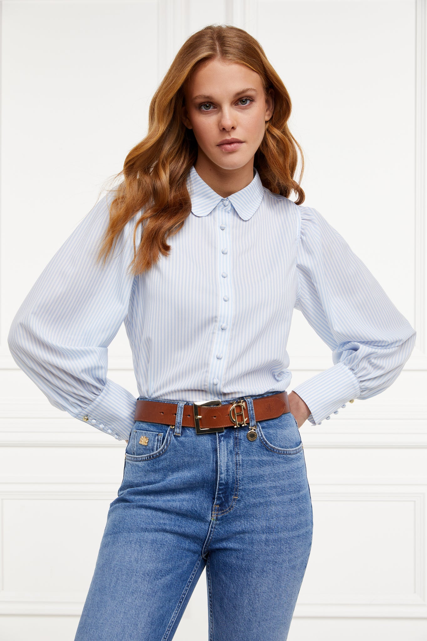 A classic fitted shirt with long sleeves and subtle puffy shoulders with thin blue and white stipe print design with extra long cuffs and rounded collar detailed with fabric buttons 
