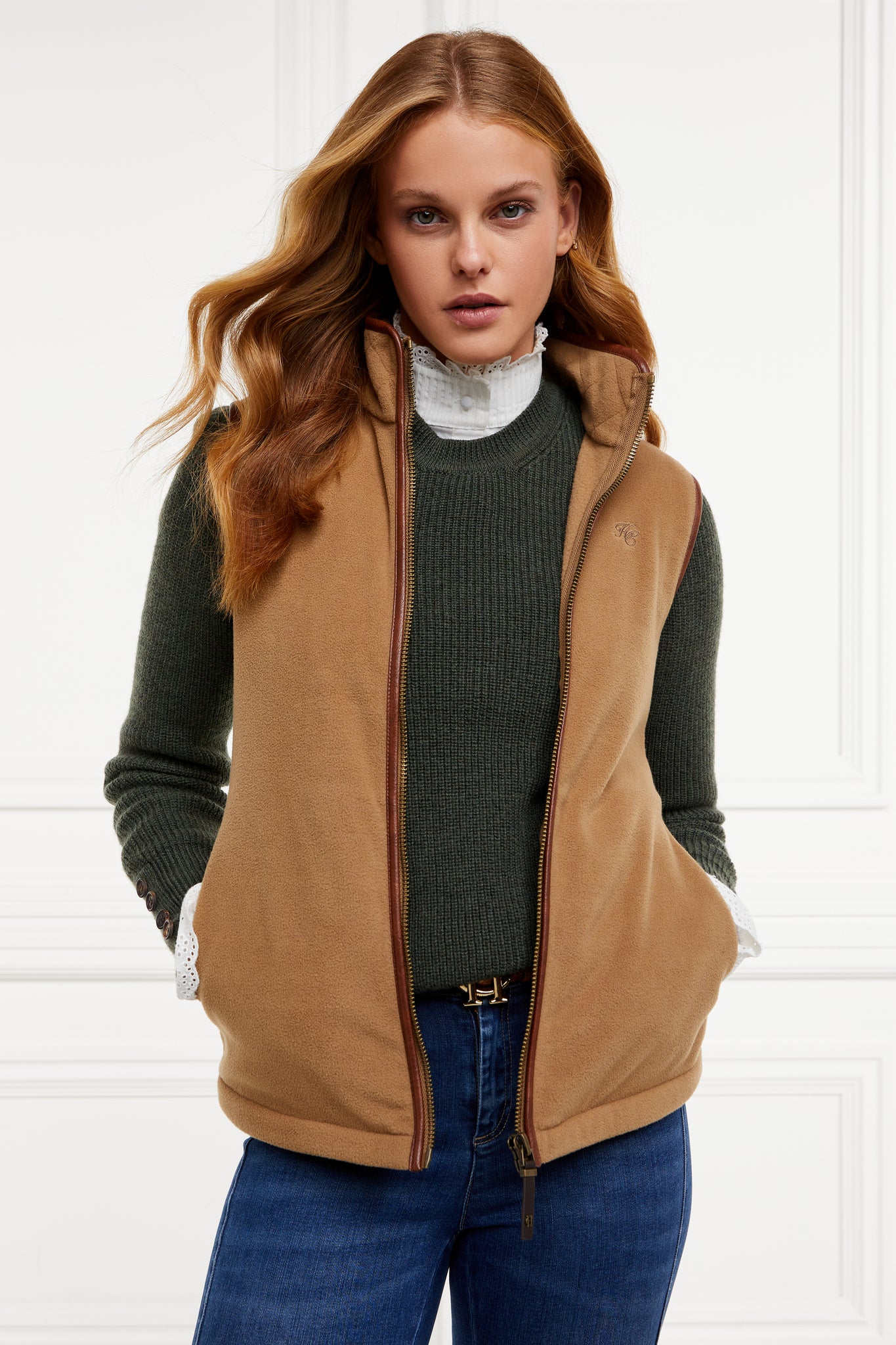 womens fleece gilet in light brown with dark brown leather piping around armholes neckline and down the front zip fastening a dark green knitted sweatshirt a white long sleeve shirt and dark denim skinny jeans