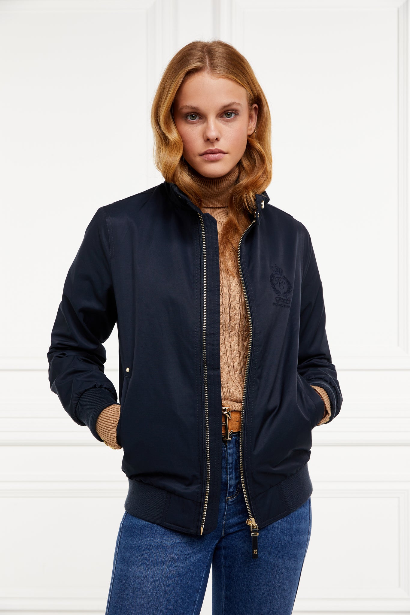 Womens navy 100% waterproof hoodless bomber style jacket with ribbed cuffs and hem, two pockets on hips  a full zip down the centre front 