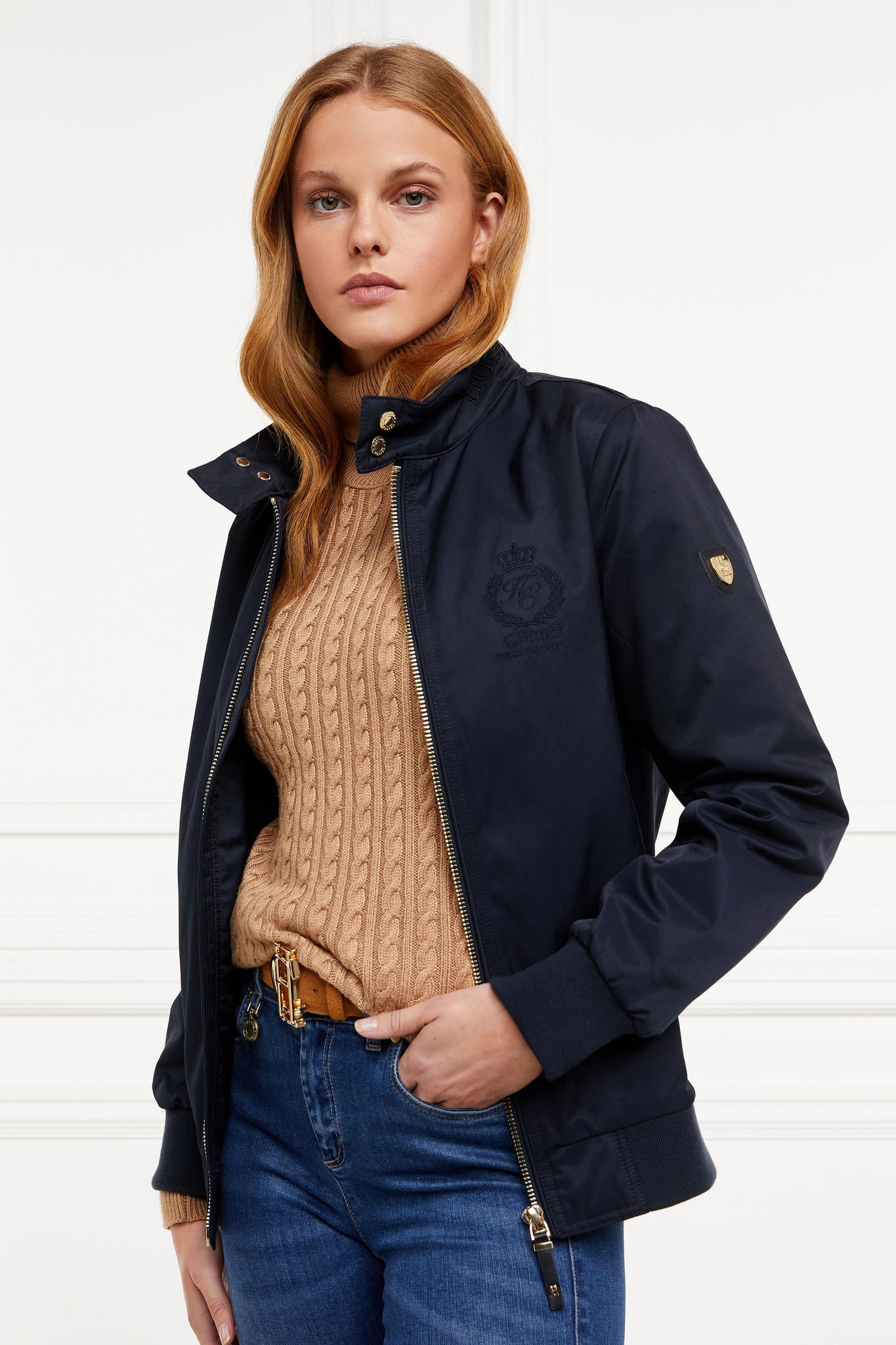 Womens navy 100% waterproof hoodless bomber style jacket with ribbed cuffs and hem, two pockets on hips  a full zip down the centre front 
