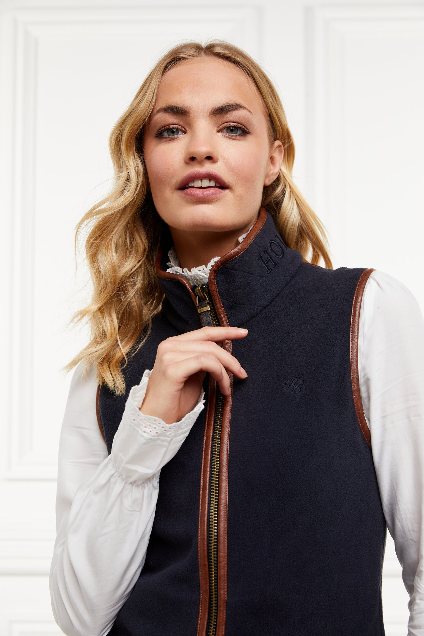 womens fleece gilet in navy with dark brown leather piping around armholes neckline and down the front zip fastening worn with a white shirt