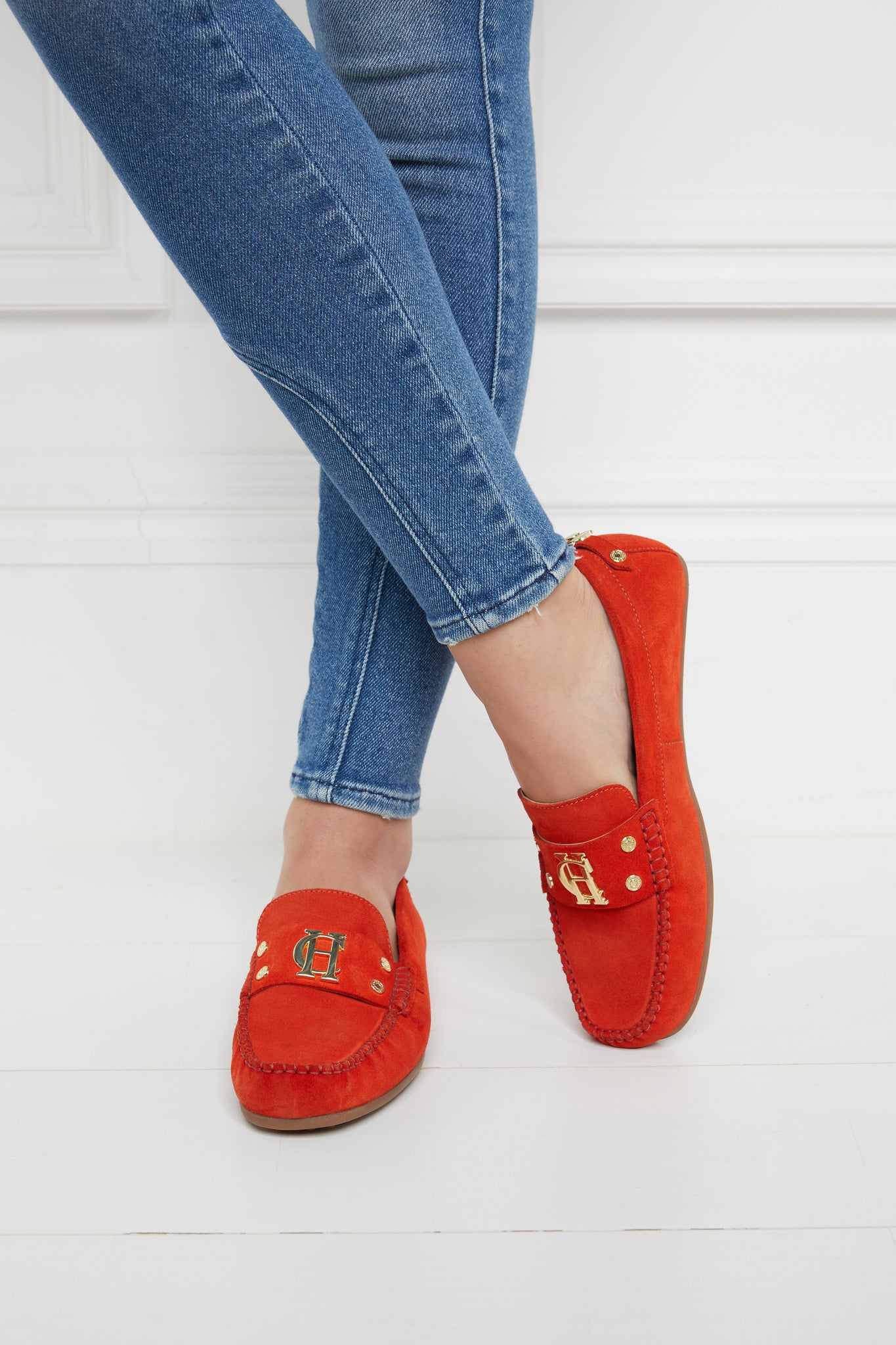 orange suede loafers with a leather sole and top stitching details and gold hardware paired with denim jeans