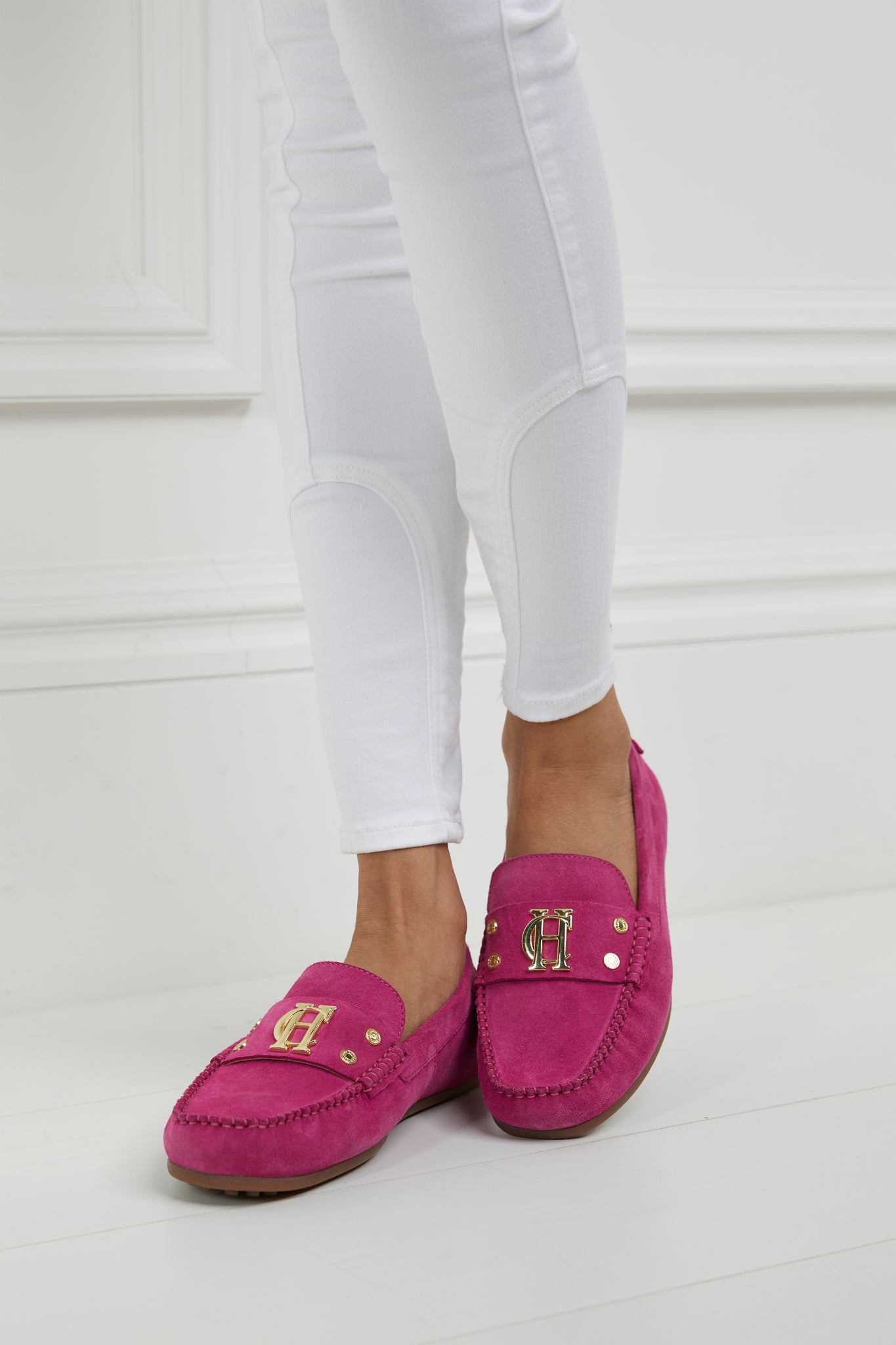 bright pink suede loafers with a leather sole and top stitching details and gold hardware paired with white skinny jeans