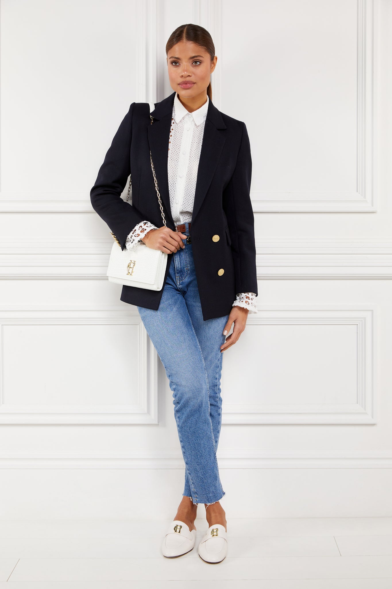 white leather backless loafers with a slightly pointed toe and gold hardware to the top worn with slim denim jeans, white broderie lace shits under a navy blazer with a white croc embossed leather clutch bag and gold chain strap