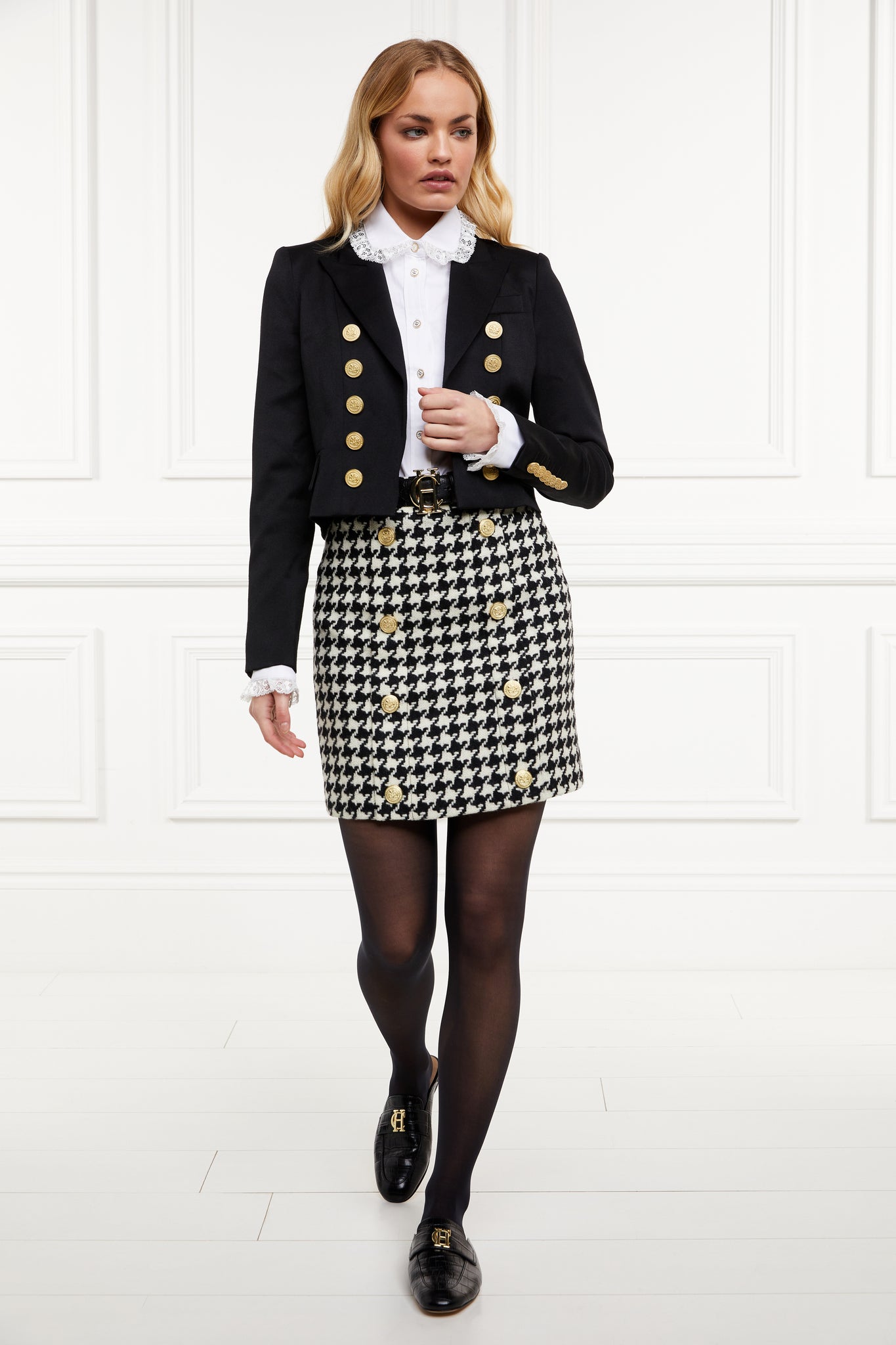 Black croc embossed leather backless loafers with a slightly pointed toe and gold hardware to the top, paired with a black and white houndstooth skirt, black tights, black croc embossed belt, white shirts with frilly collar and black cropped blazer