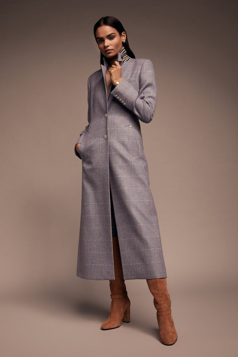 Model wearing purple tweed coat with silver buttons and tan heeled boots