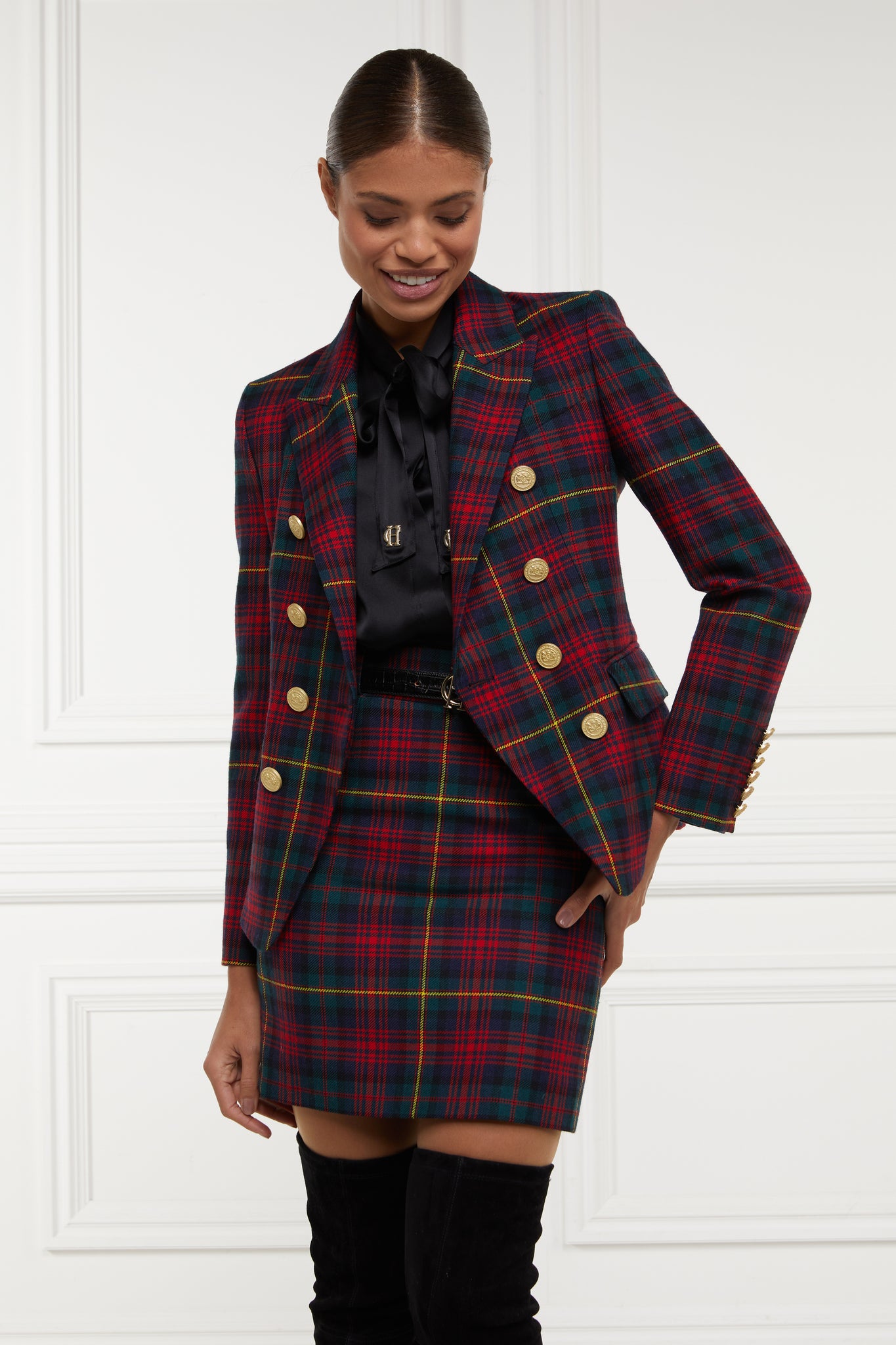 British made double breasted blazer that fastens with a single button hole to create a more form fitting silhouette with two pockets and gold button detailing this blazer is made from  red green navy and yellow logan tartan worn with black shirt and skirt in matching tartan pattern