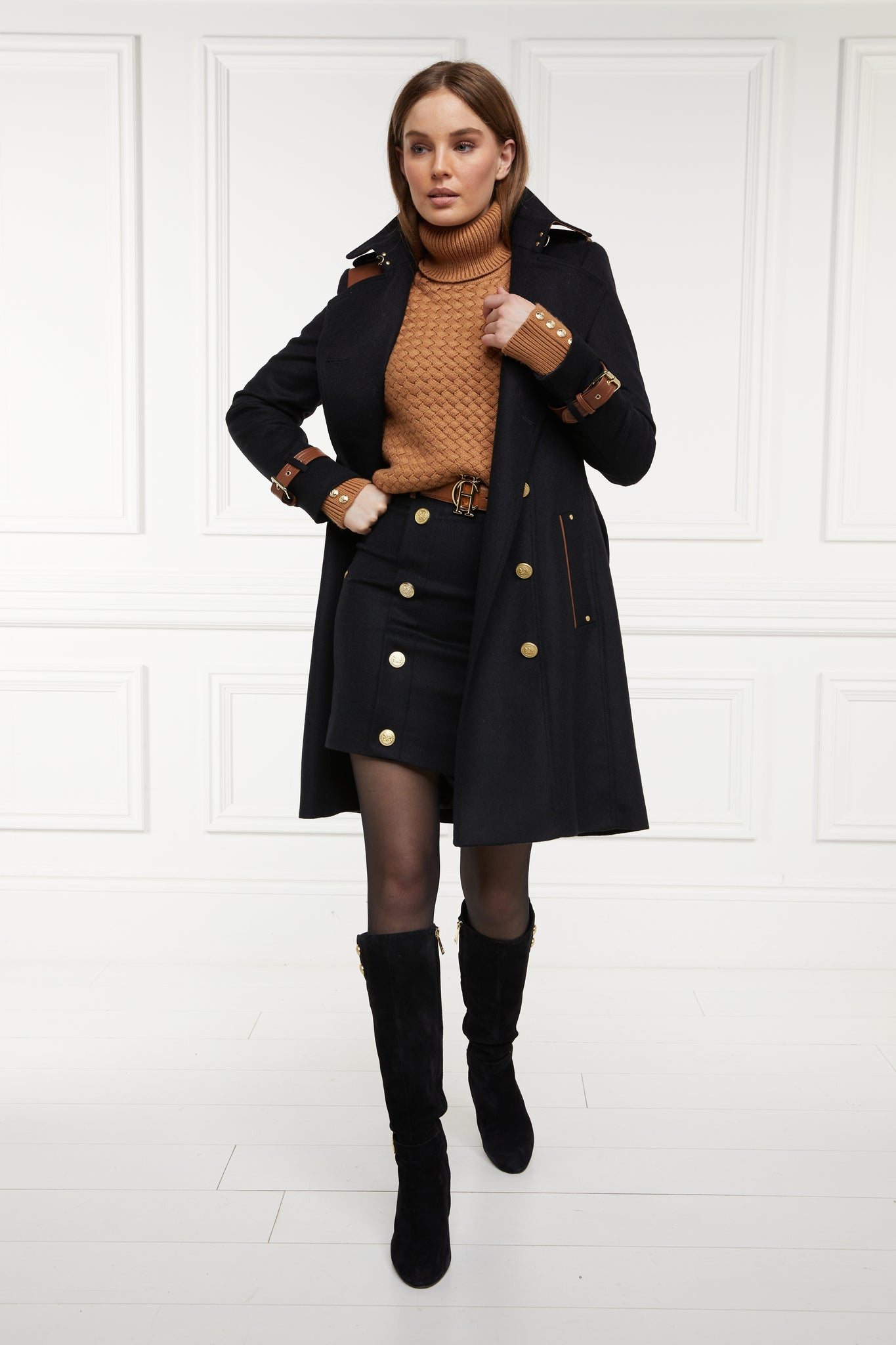 womens black and tan wool pencil mini skirt with concealed zip fastening on centre back and gold rivets down front worn with mid length trench coat in matching colourway