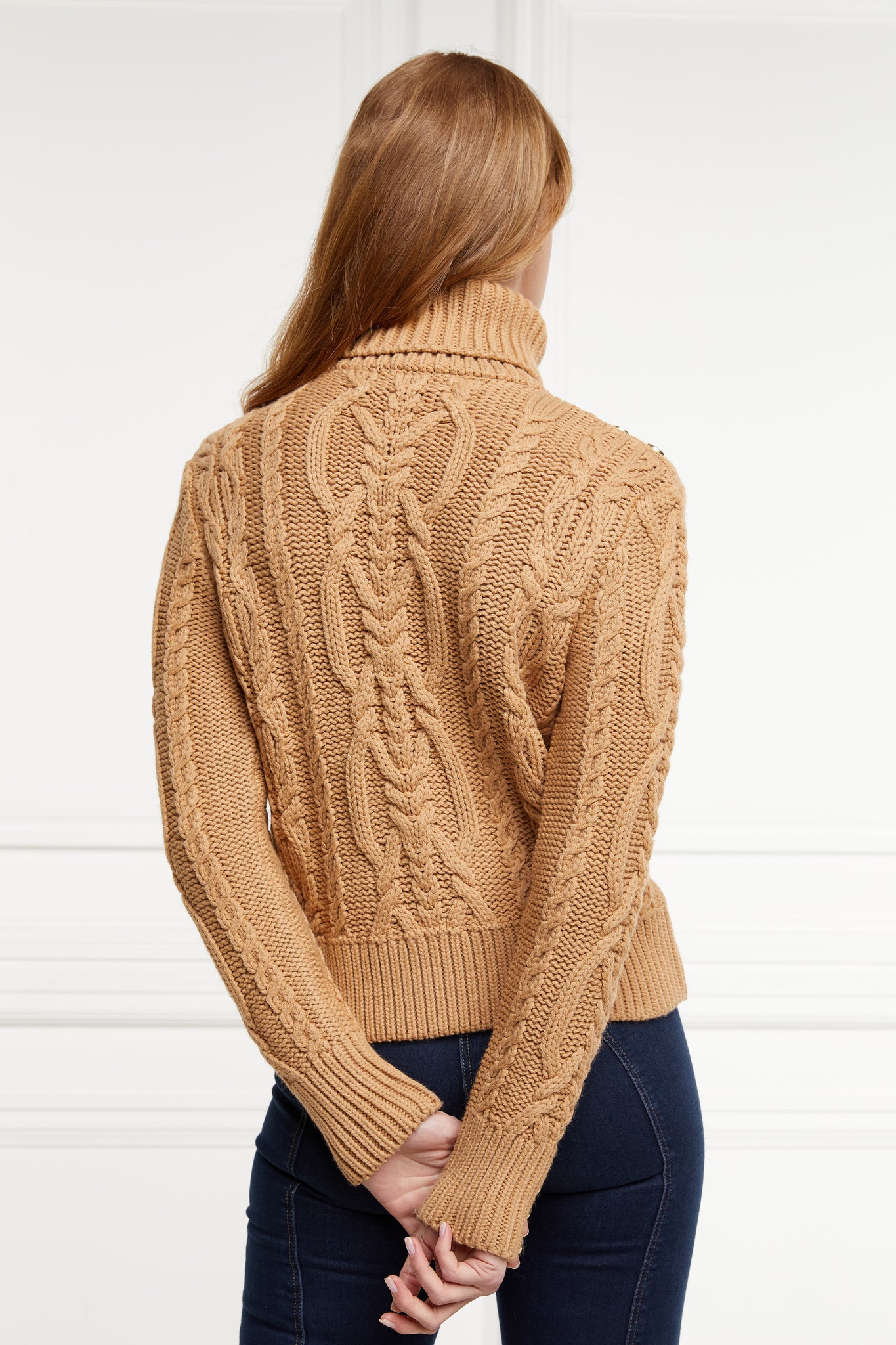 a chunky cable knit roll neck jumper in camel with dropped shoulders and thick ribbed cable trims and gold buttons on cuffs and collar
