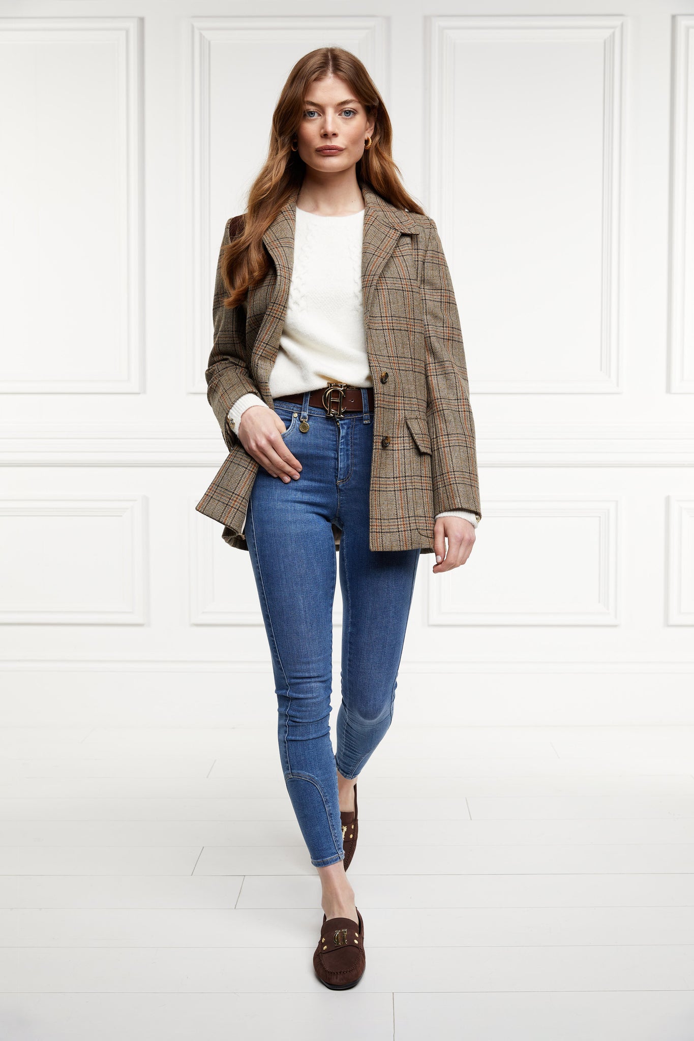 Classic brown suede loafers with a leather sole and top stitching details and gold hardware paired with skinny denim jeans, brown belt, cream crew neck knit and bredon tweed blazer