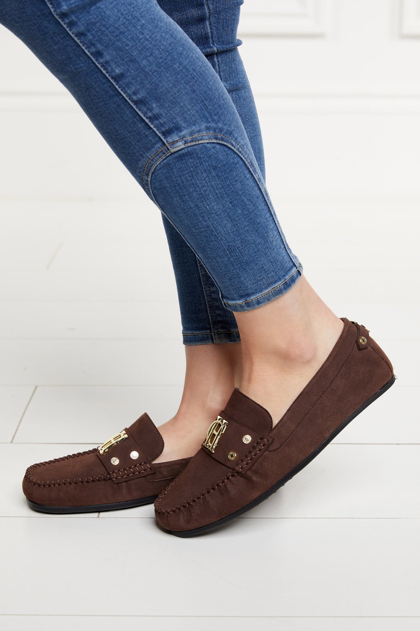 Classic brown suede loafers with a leather sole and top stitching details and gold hardware with skinny denim jeans