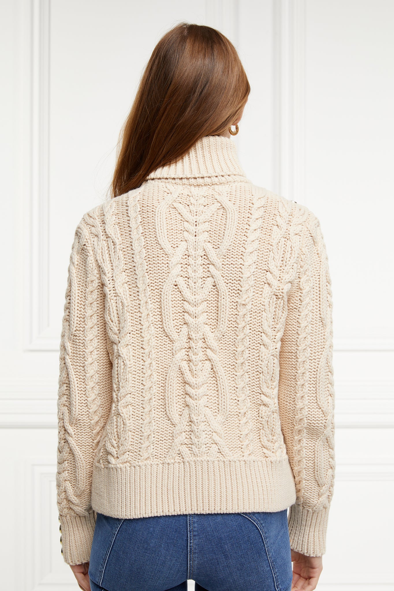a chunky cable knit roll neck jumper in oatmeal with dropped shoulders and thick ribbed cable trims and gold buttons on cuffs and collar