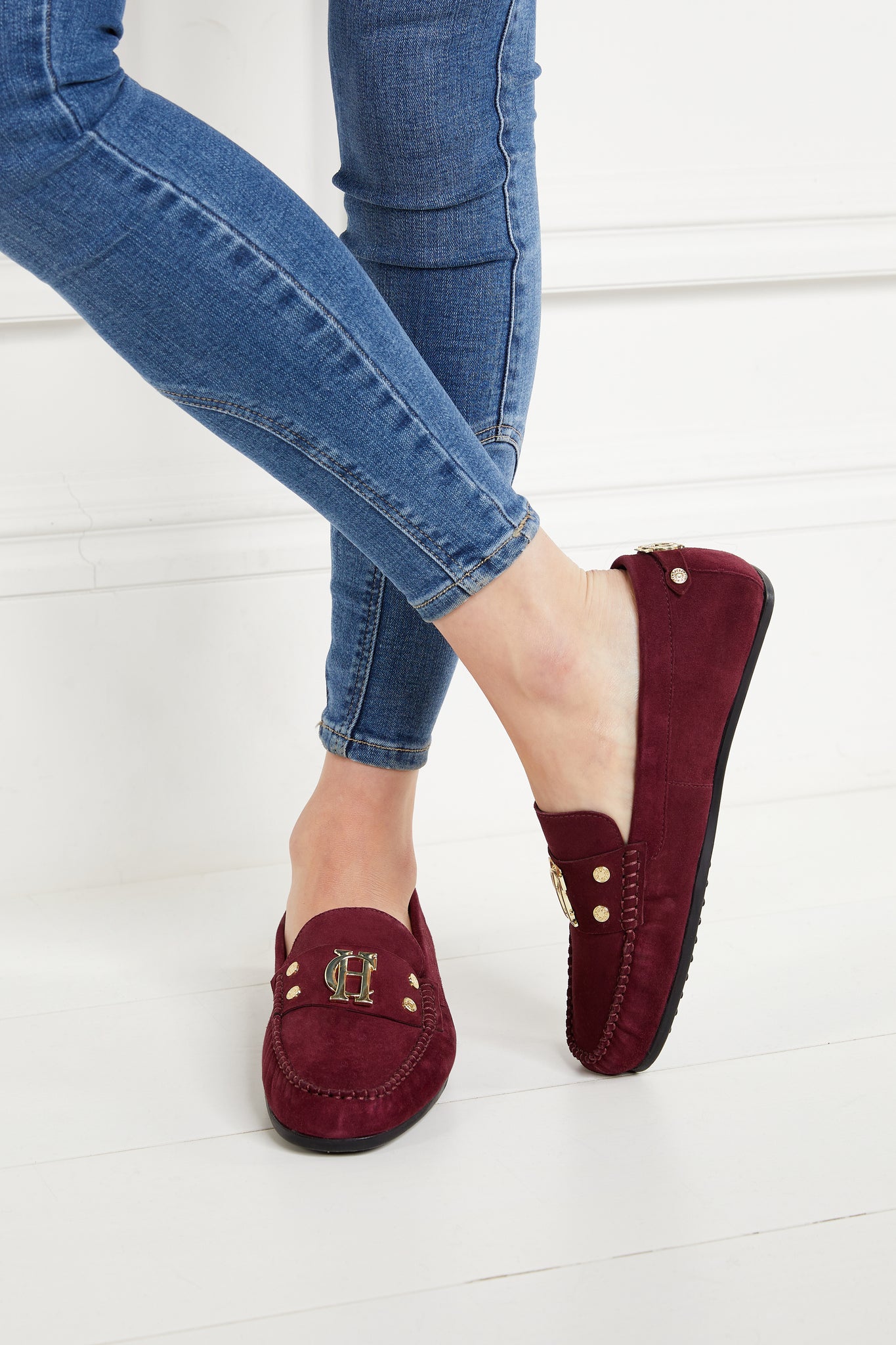 classic deep red suede loafers with a leather sole and top stitching details and gold hardware paired with skinny denim jeans