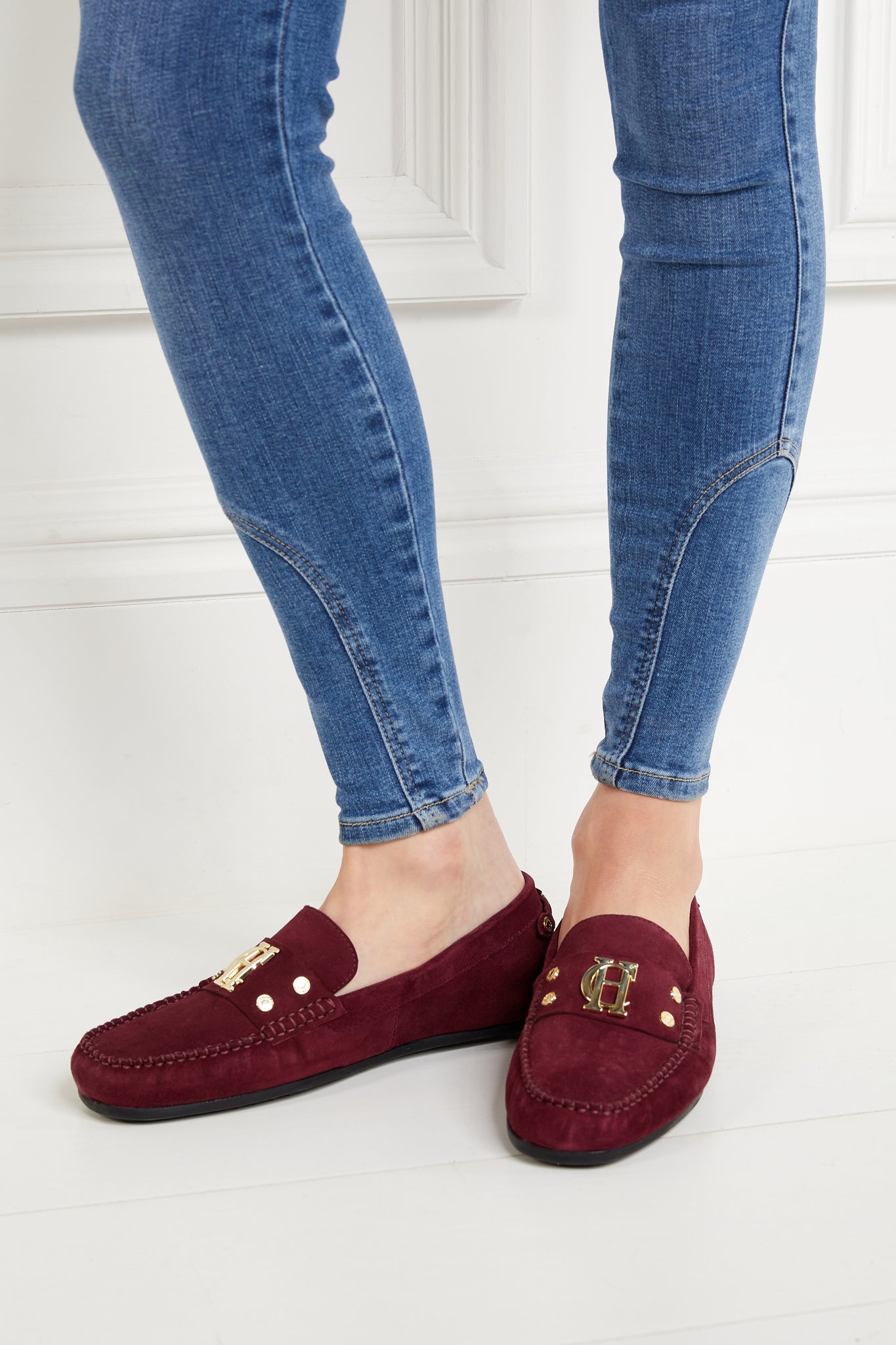 classic deep red suede loafers with a leather sole and top stitching details and gold hardware paired with skinny denim jeans