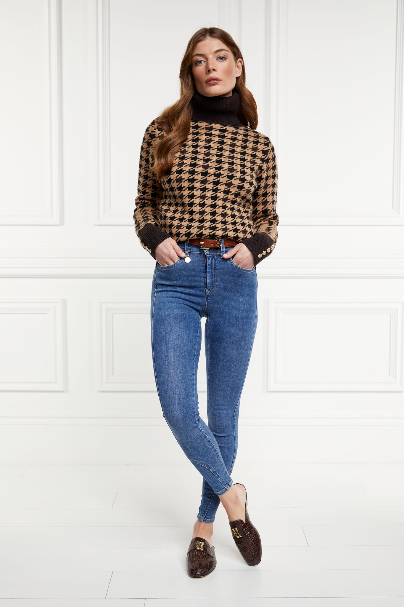 Model wearing Brown croc embossed leather backless loafers with a slightly pointed toe and gold hardware to the top paired with a camel roll neck jumper, denim skinny jeans and a slim brown leather belt