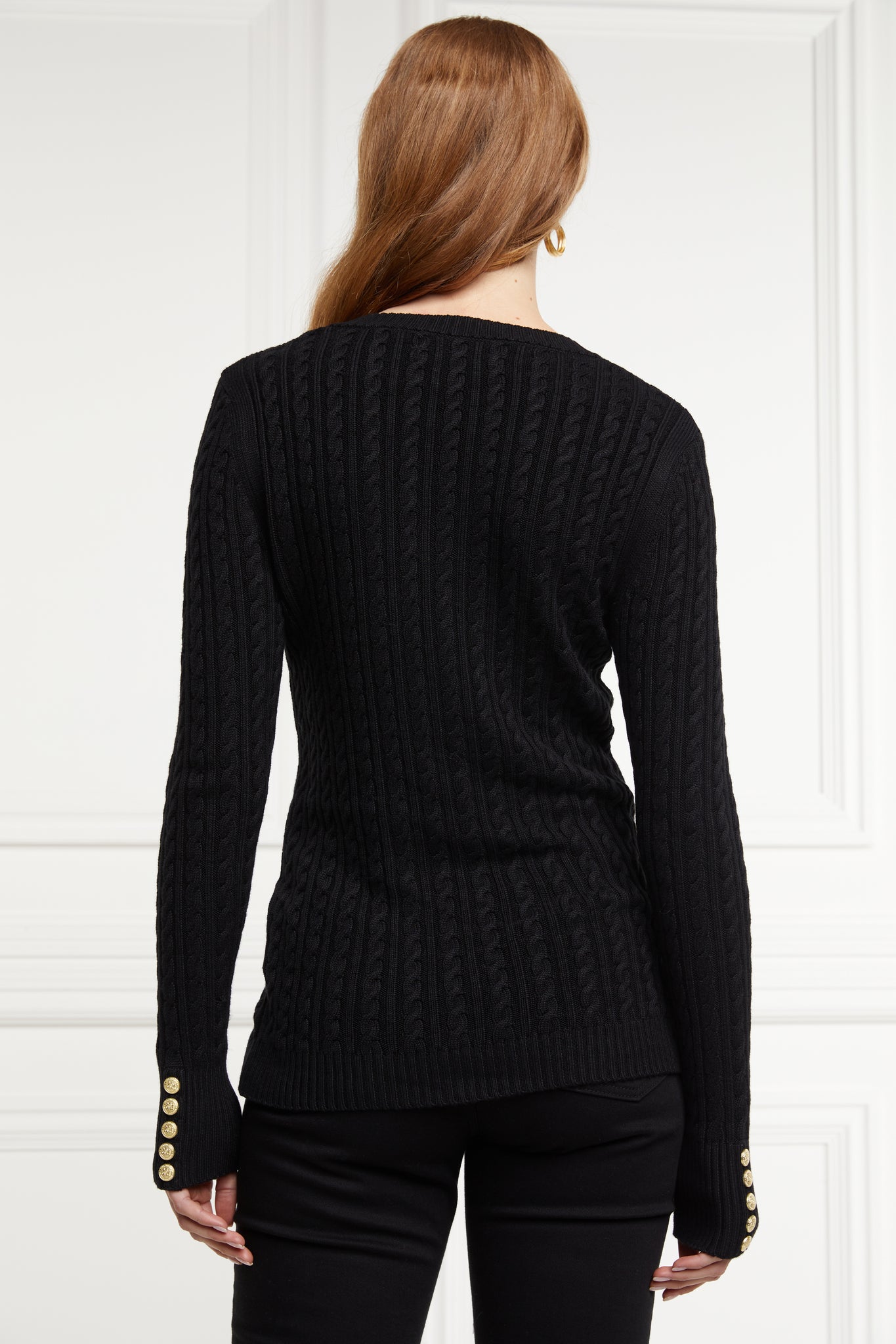 back of womens lightweight v neck cable knit jumper in black detailed with gold buttons at the cuffs