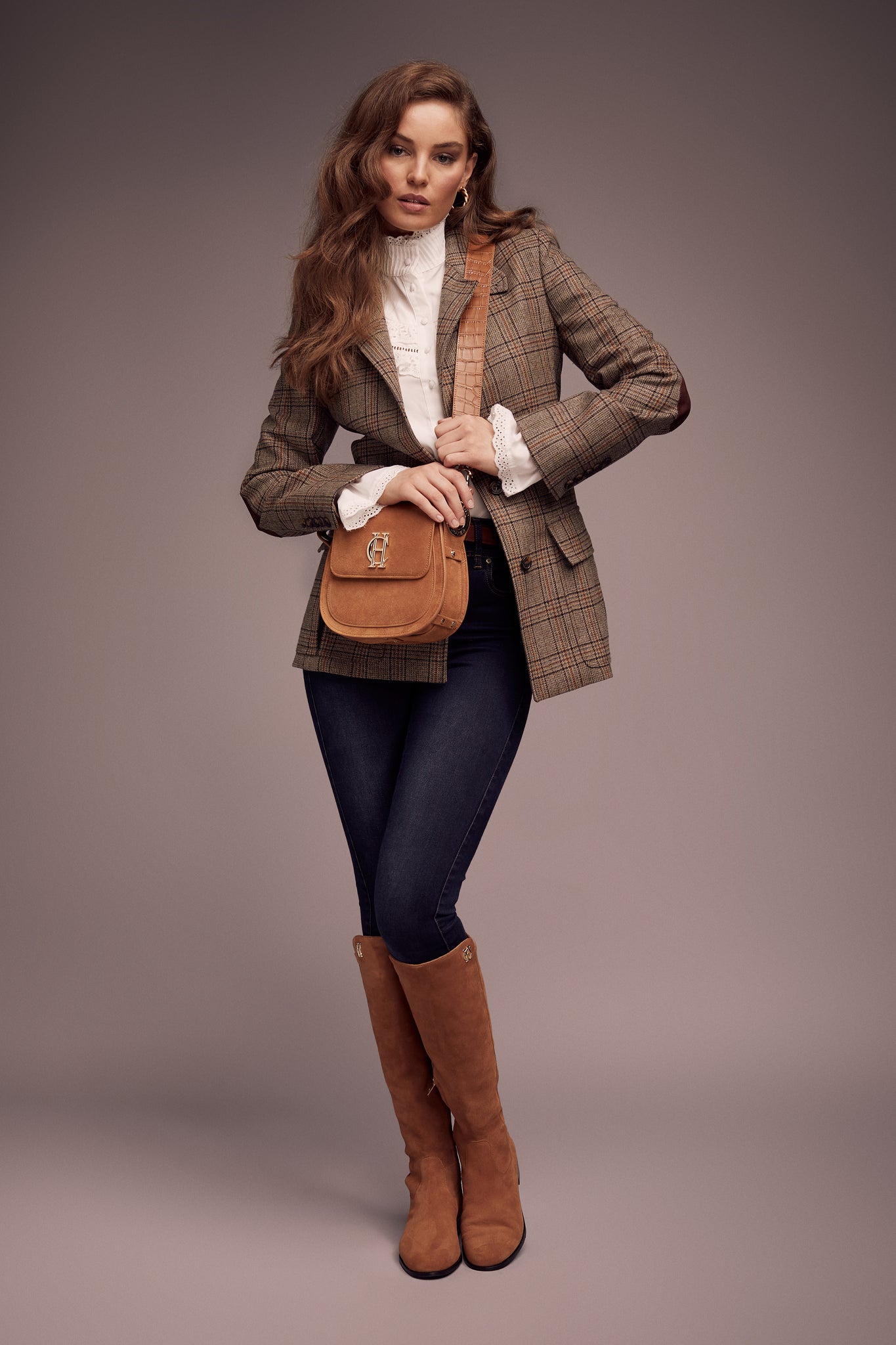 womens classic slim fit single breasted blazer in brown and orange tweed with lower patch pockets with concealed button flap contrast brown suede shoulder gun patch with elbow patches and horn button finish on cuffs and front worn with navy jeans tan knee high boots and white shirt