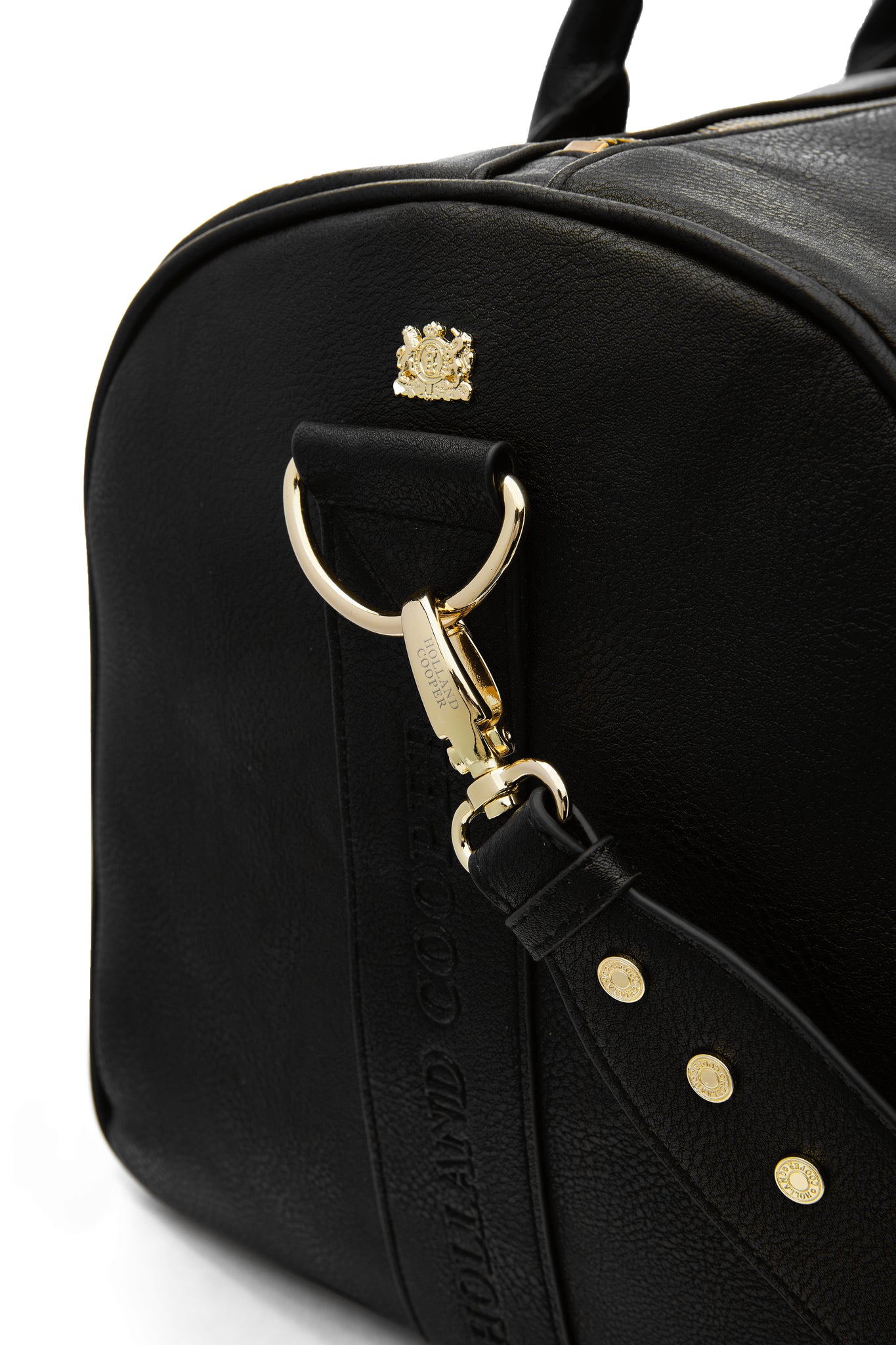 close up of D ring with attached black faux leather bag strap on black faux leather travel holdall