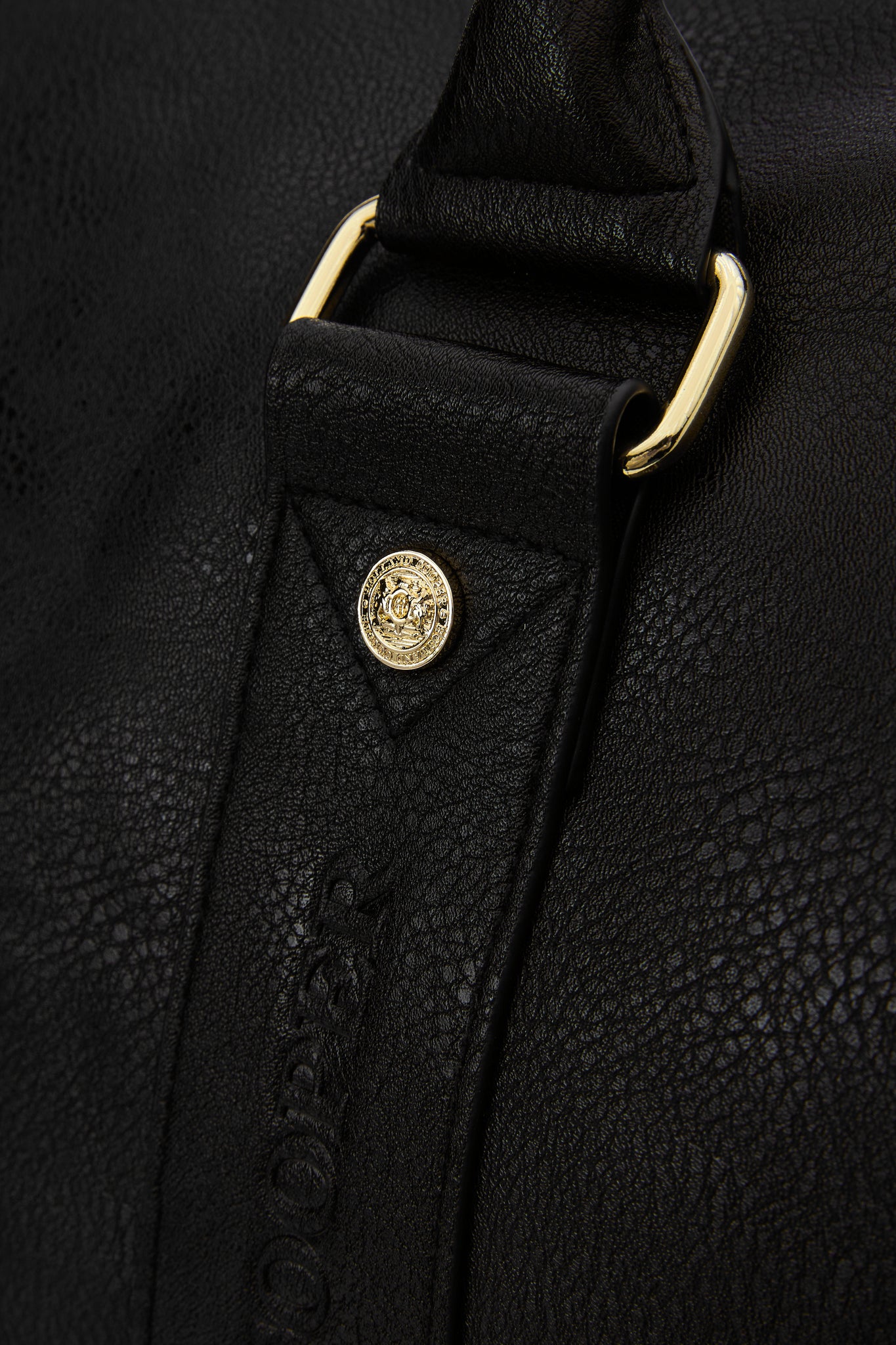detail close up of gold hardware details on black faux leather travel holdall bag
