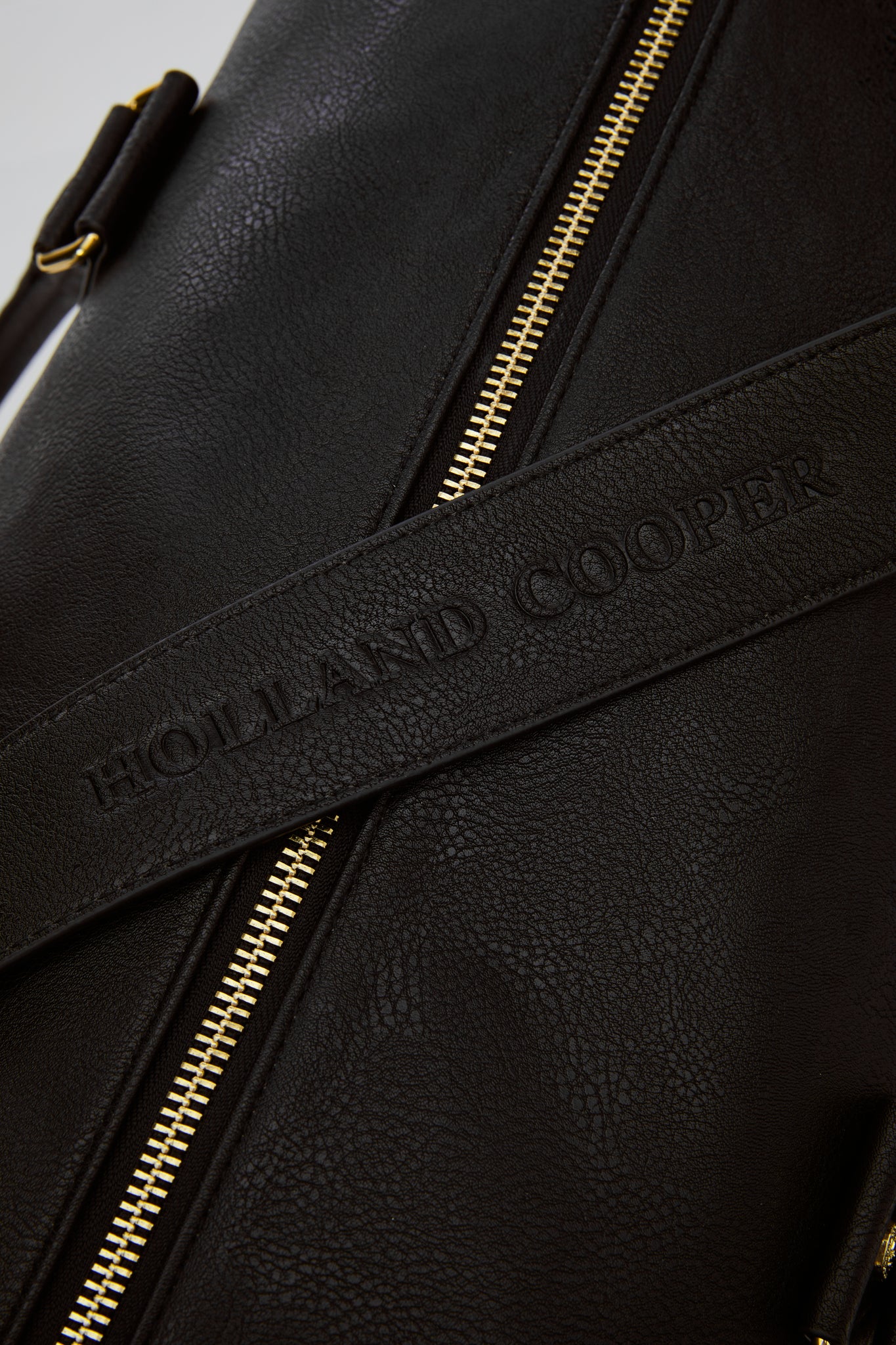 close up of holland cooper embossed black faux leather holdall strap