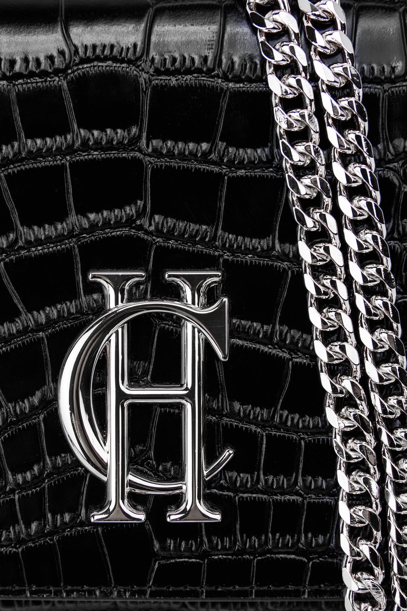 close up of womens black croc embossed leather clutch bag with silver hardware and silver chain