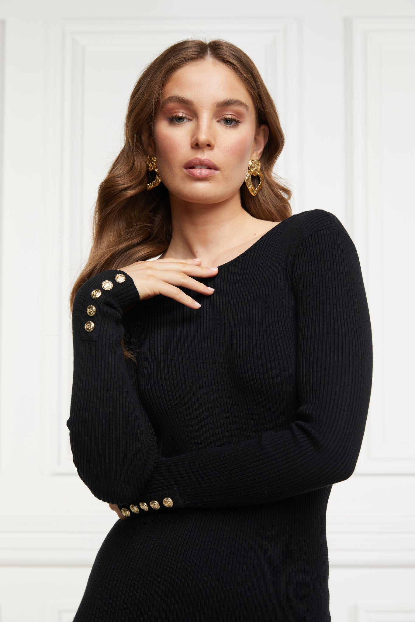 womens black long sleeved body-contouring ribbed backless midi dress with gold chain along back and gold buttons on the cuffs