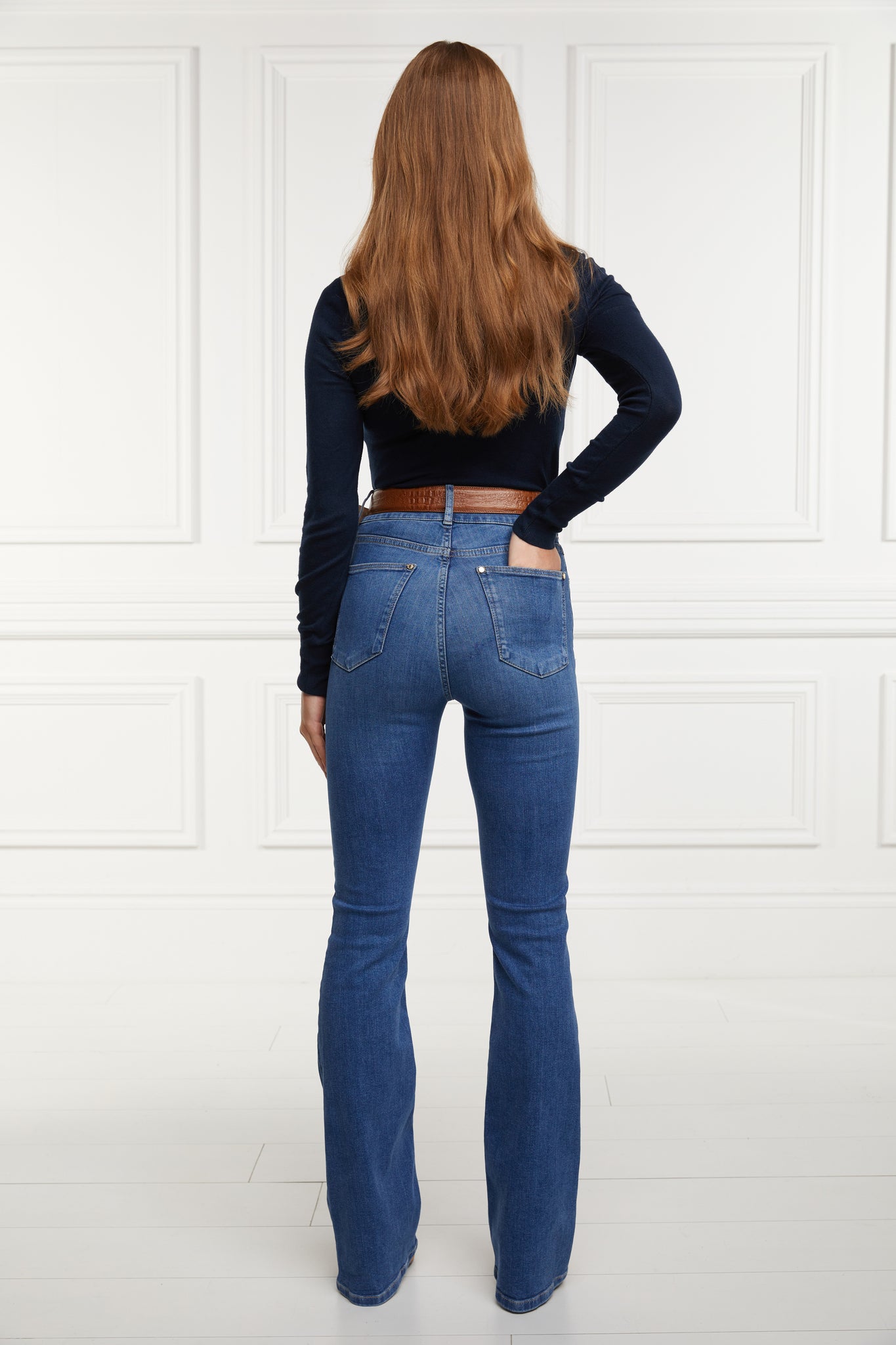 back of womens high rise blue denim flared jean with centre front zip fly fastening with two open pockets at the front and back and gold hardware on back waistband