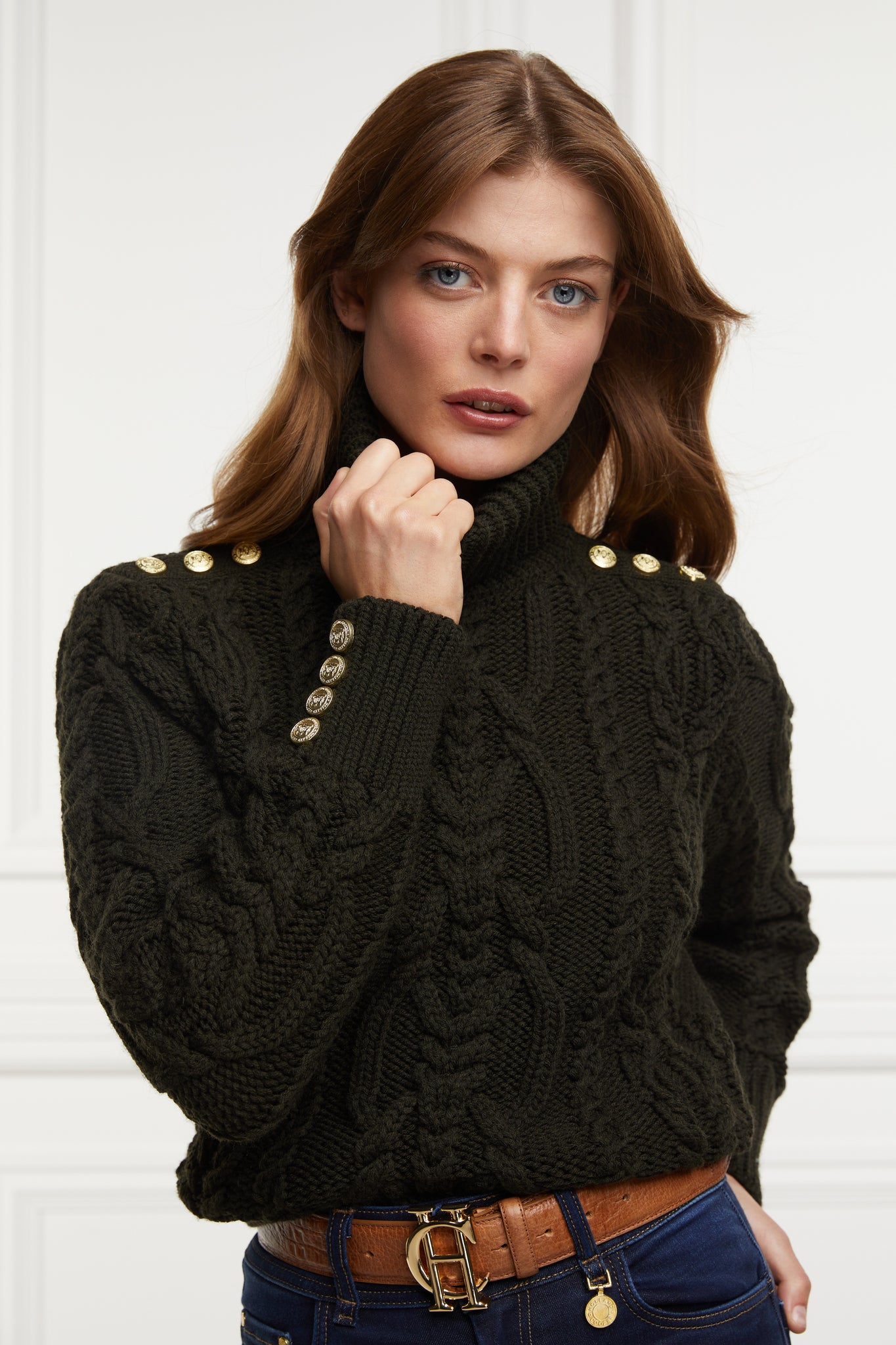 a chunky cable knit roll neck jumper in fern green with dropped shoulders and thick ribbed cable trims and gold buttons on cuffs and collar