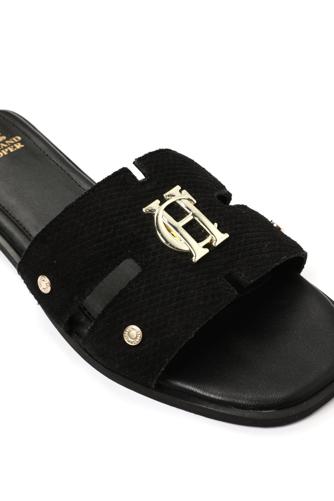 Close up of black suede sliders with a black leather sole and gold hardware. 