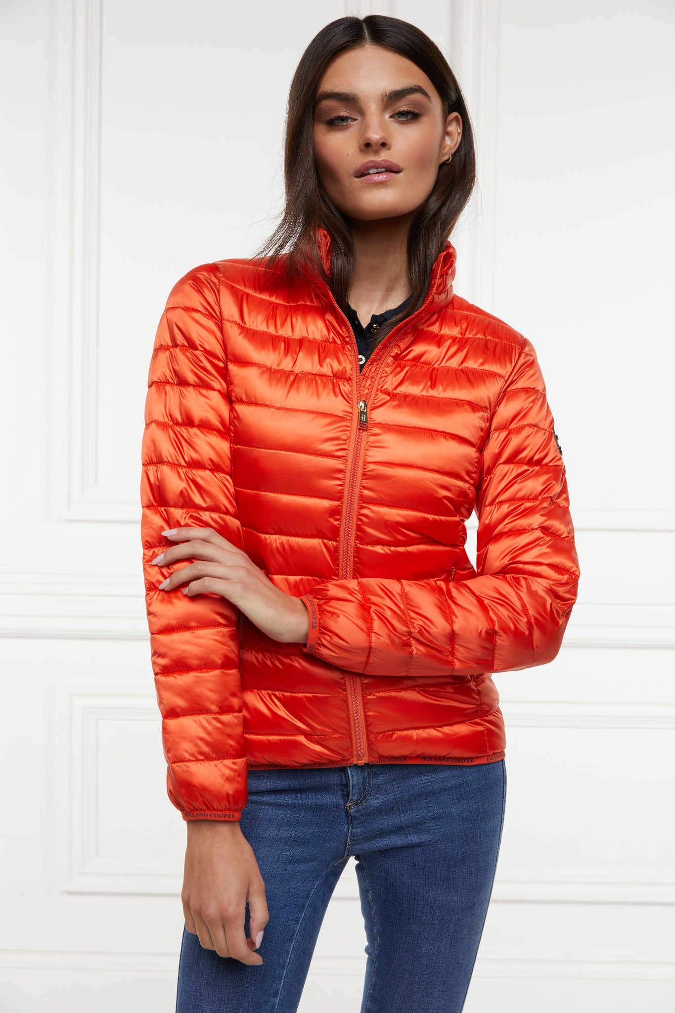 womens lightweight hoodless padded orange jacket with embroidery detail on back high neck and elasticated cuffs and hem. easily packs away into separate small bag of the same colour with handle 