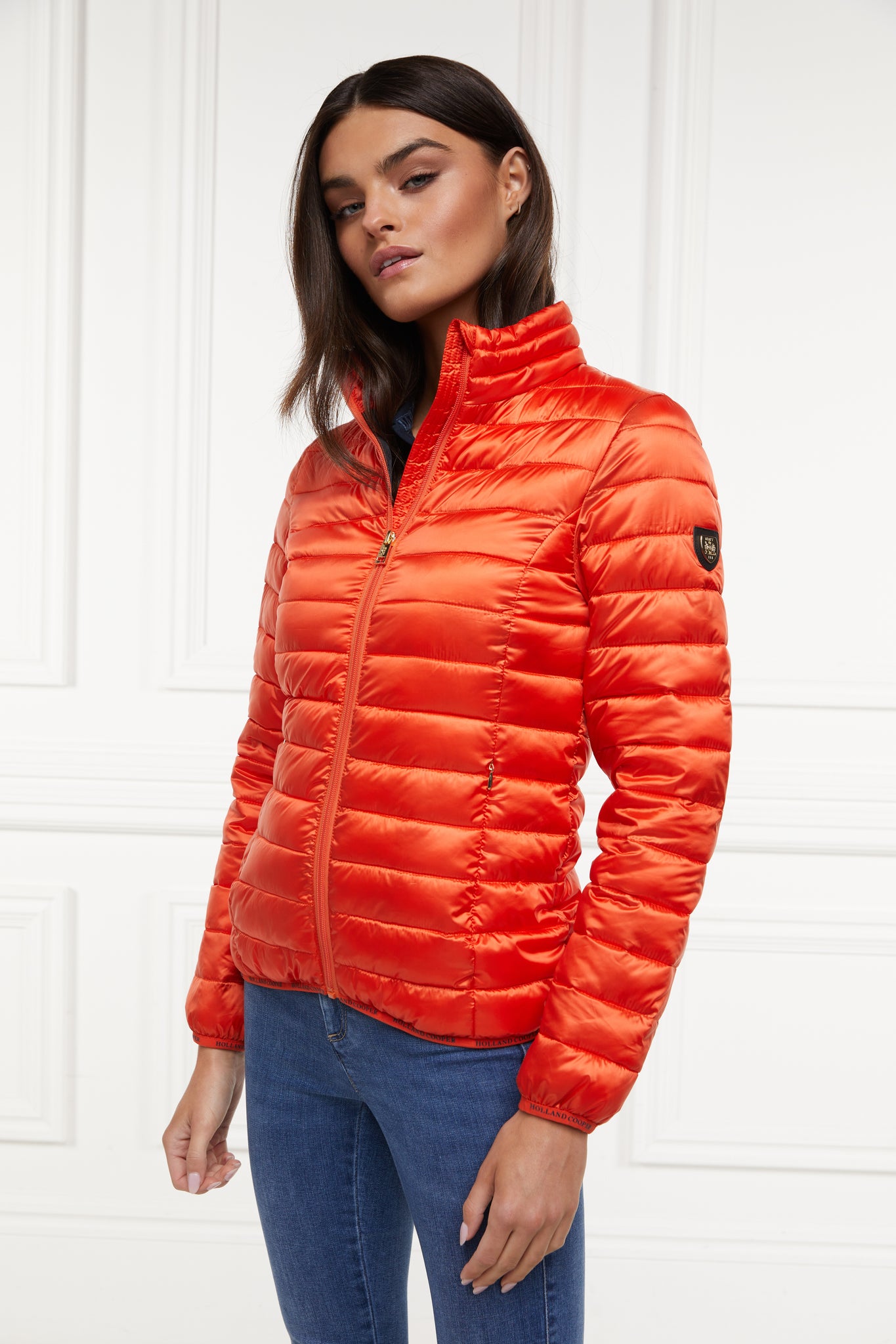 womens lightweight hoodless padded orange jacket with embroidery detail on back high neck and elasticated cuffs and hem. easily packs away into separate small bag of the same colour with handle 