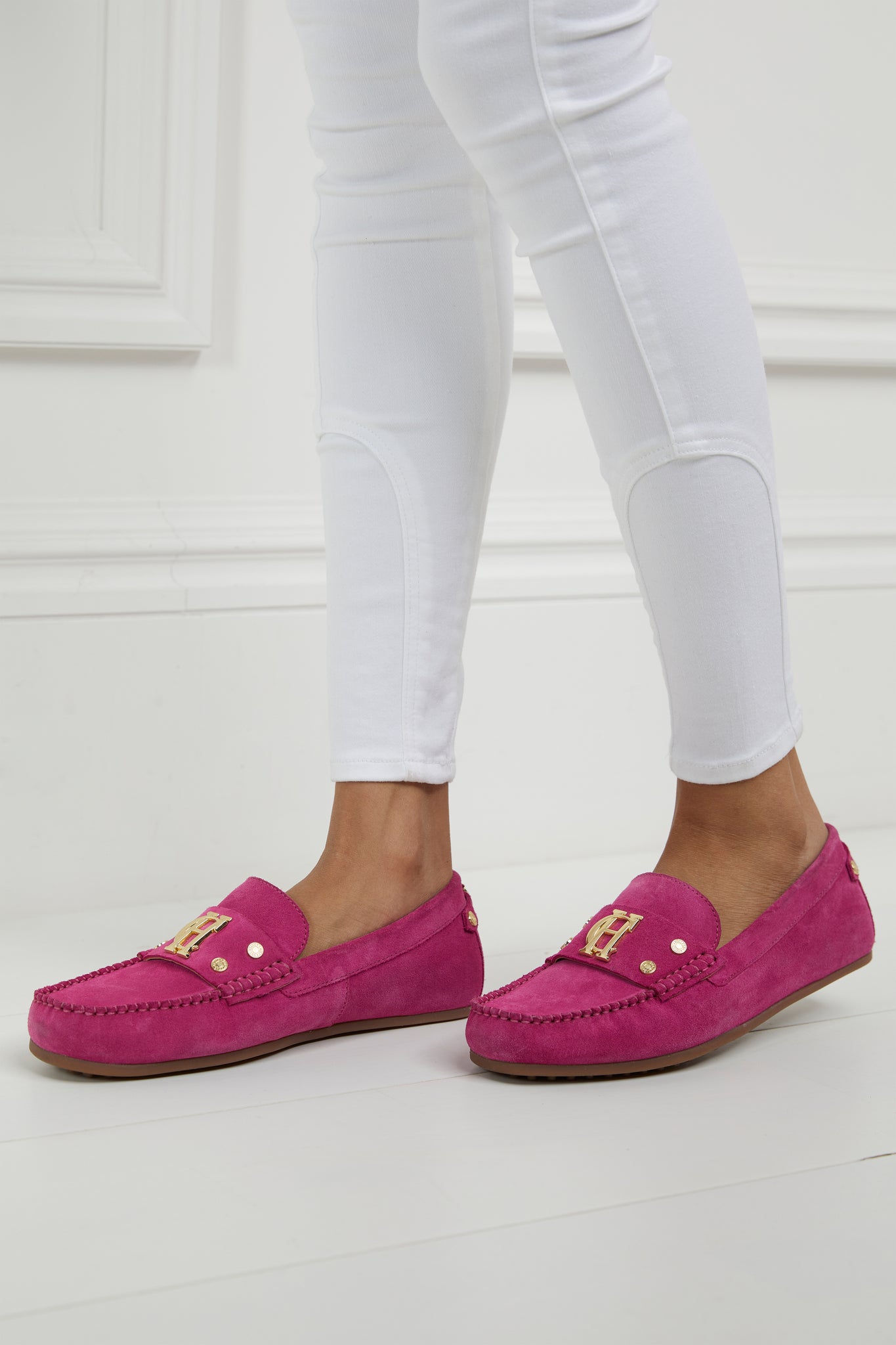 bright pink suede loafers with a leather sole and top stitching details and gold hardware paired with white skinny jeans
