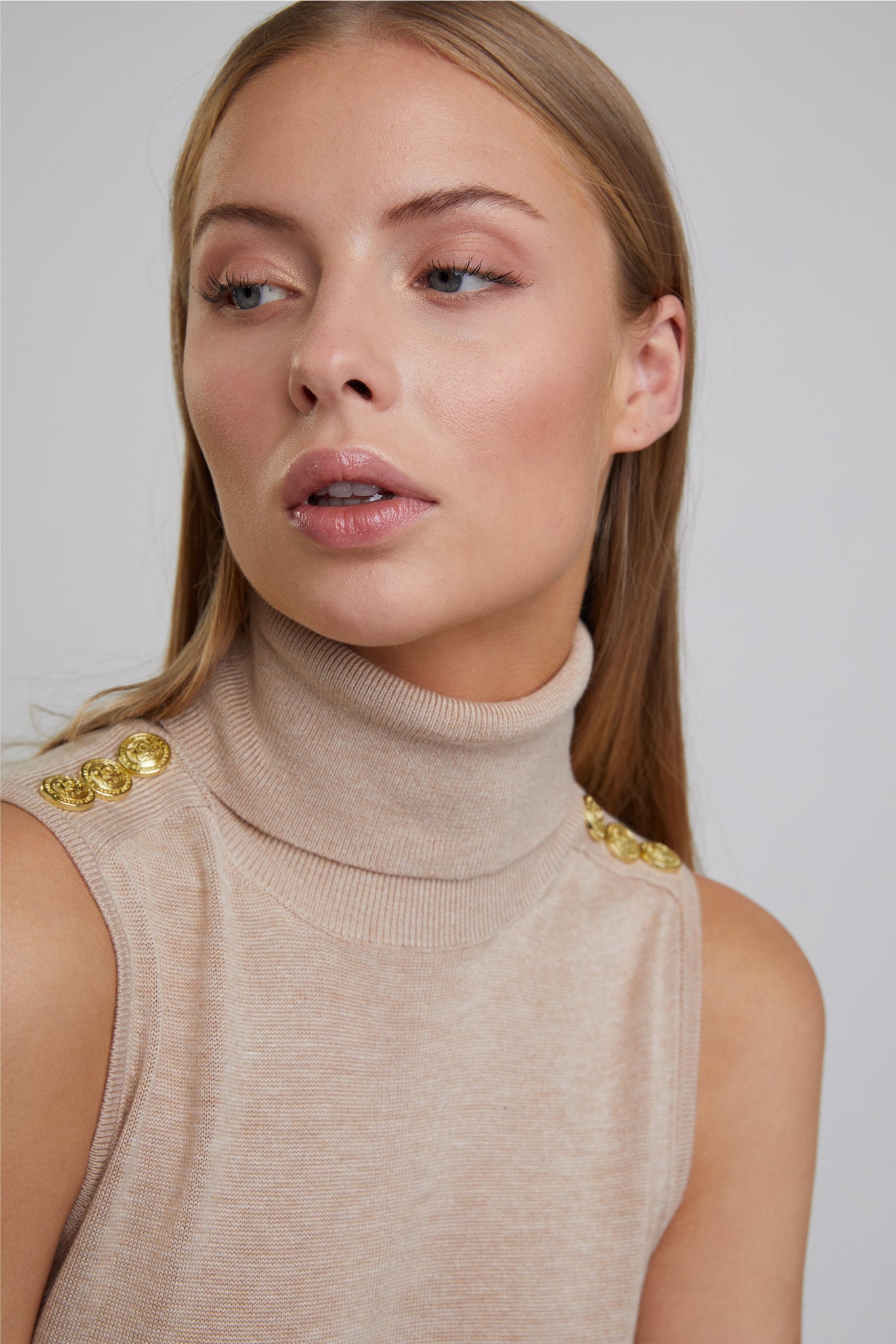 ribbed roll neck detail on fitted lightweight sleeveless rollneck knit in camel with gold button detail across shoulders