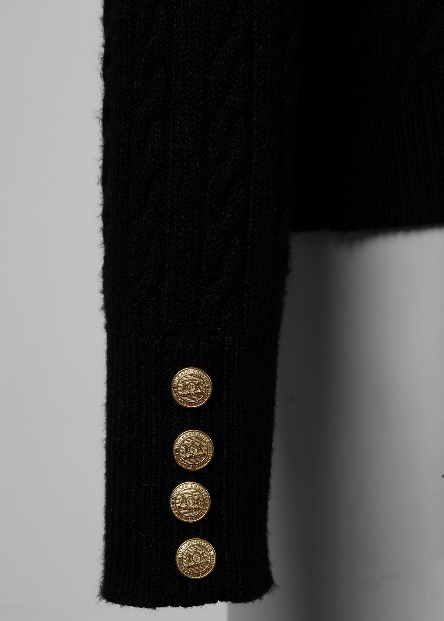 gold button detail on cuffs on womens cable knit jumper in black with ribbed roll neck cuffs and hem