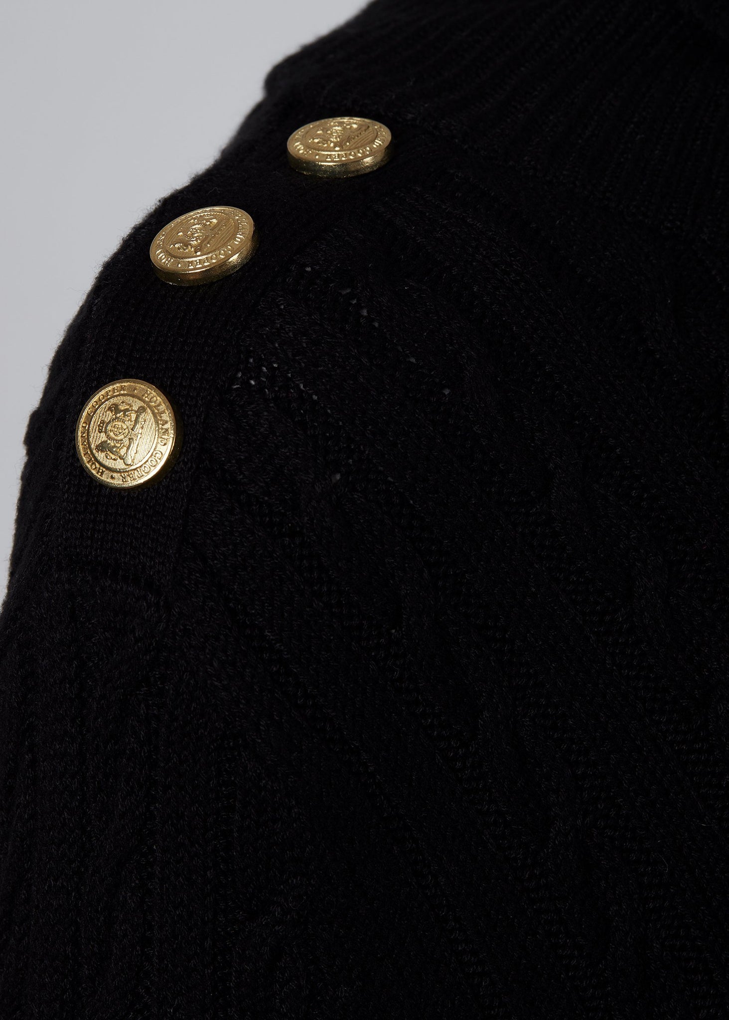 gold button detail on shoulders of womens cable knit jumper in black with ribbed roll neck cuffs and hem
