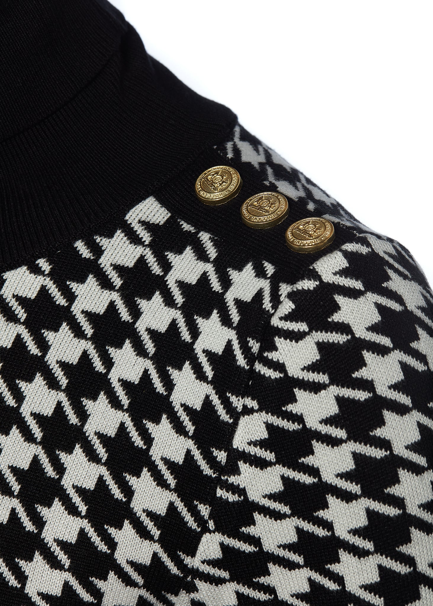 gold button detail on shoulders of a classic black and white houndstooth jumper with contrast black roll neck collar