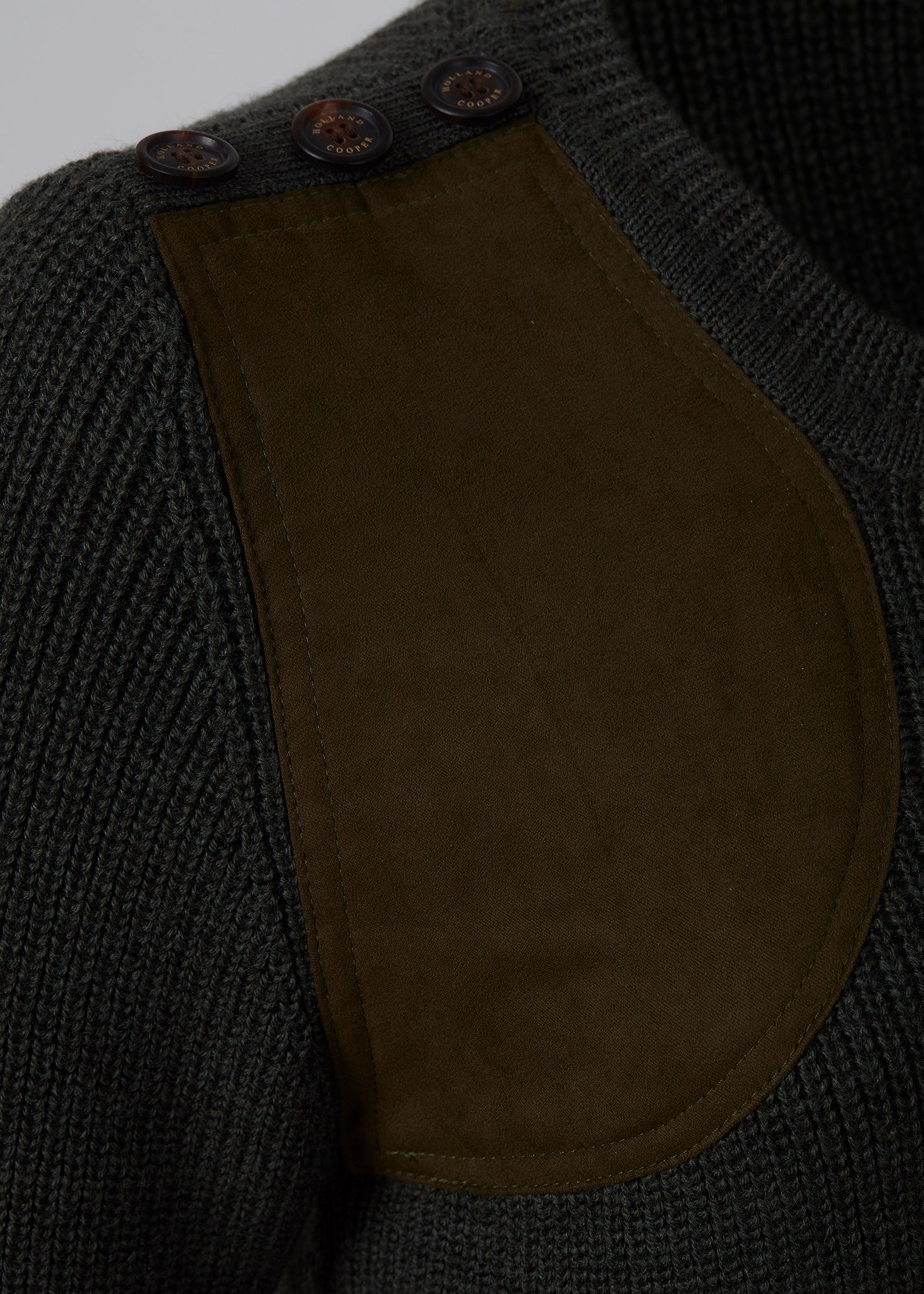 horn button detail accross shoulder and brown faux suede gunpatch detail on classic crew neck slim fit merino wool jumper in forest green with quilted elbow patches in the same brown suede material