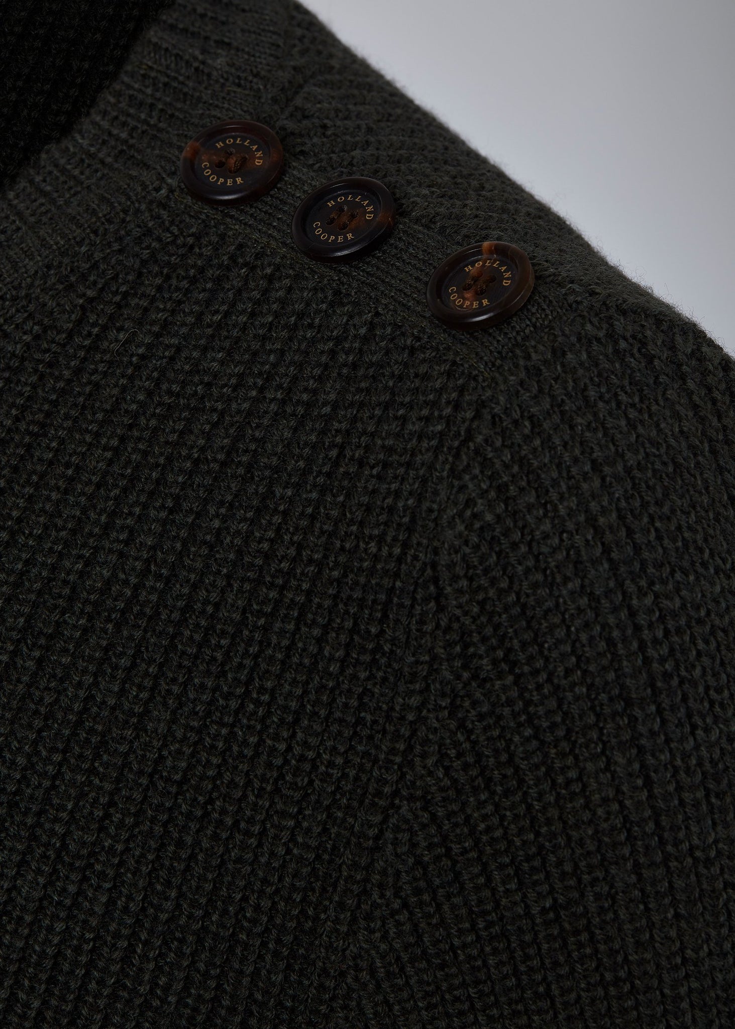 horn button detail across shoulders of classic crew neck slim fit merino wool jumper in forest green with brown faux suede gunpatch on shoulder and quilted elbow patches in the same brown suede material