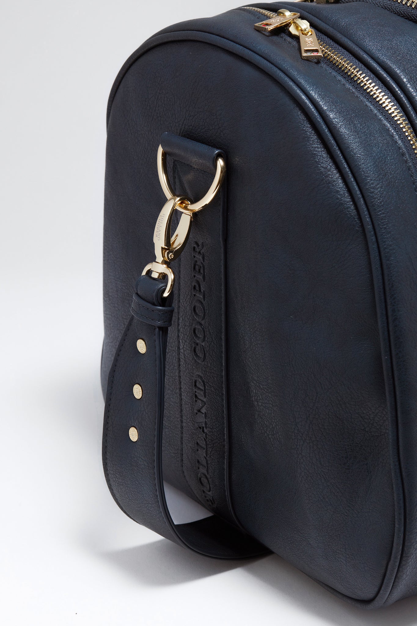 close up of D ring with bag strap linked onto of navy faux leather equestrian kit bag 