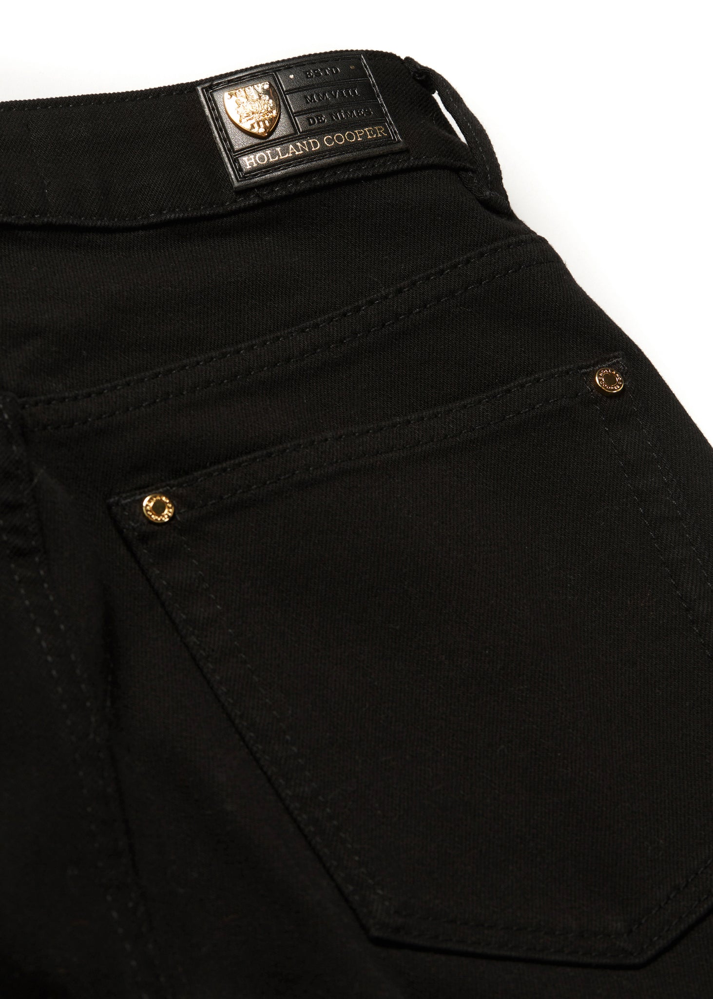 back pocket detail on womens high rise black denim slim fit jean with raw hem and two open pockets on the front and back with gold stirrup charm to the belt loop