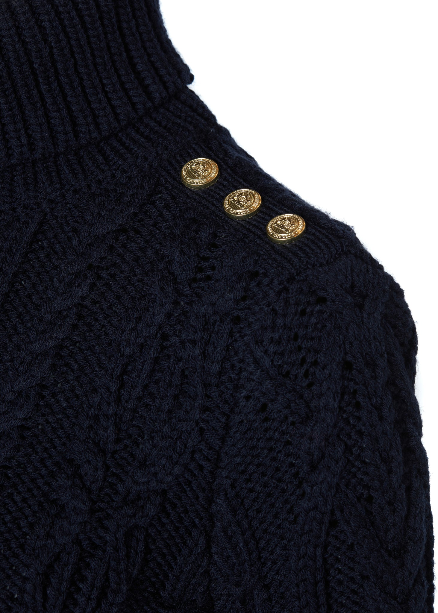 gold button detail across shoulders of a chunky cable knit roll neck jumper in navy with dropped shoulders and thick ribbed cable trims and gold buttons on cuffs and collar