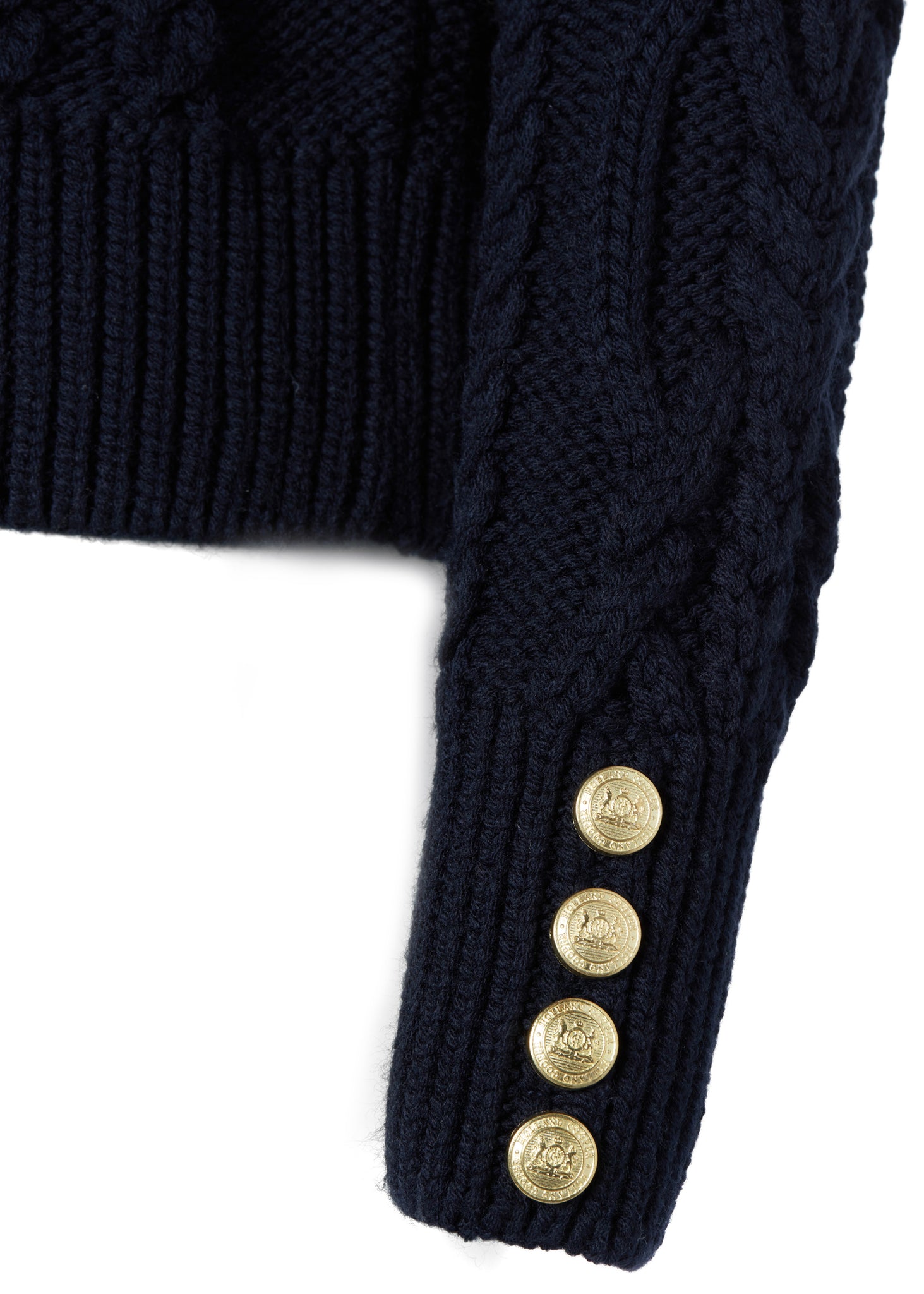 gold button detail on cuffs of a chunky cable knit roll neck jumper in navy with dropped shoulders and thick ribbed cable trims and gold buttons on cuffs and collar