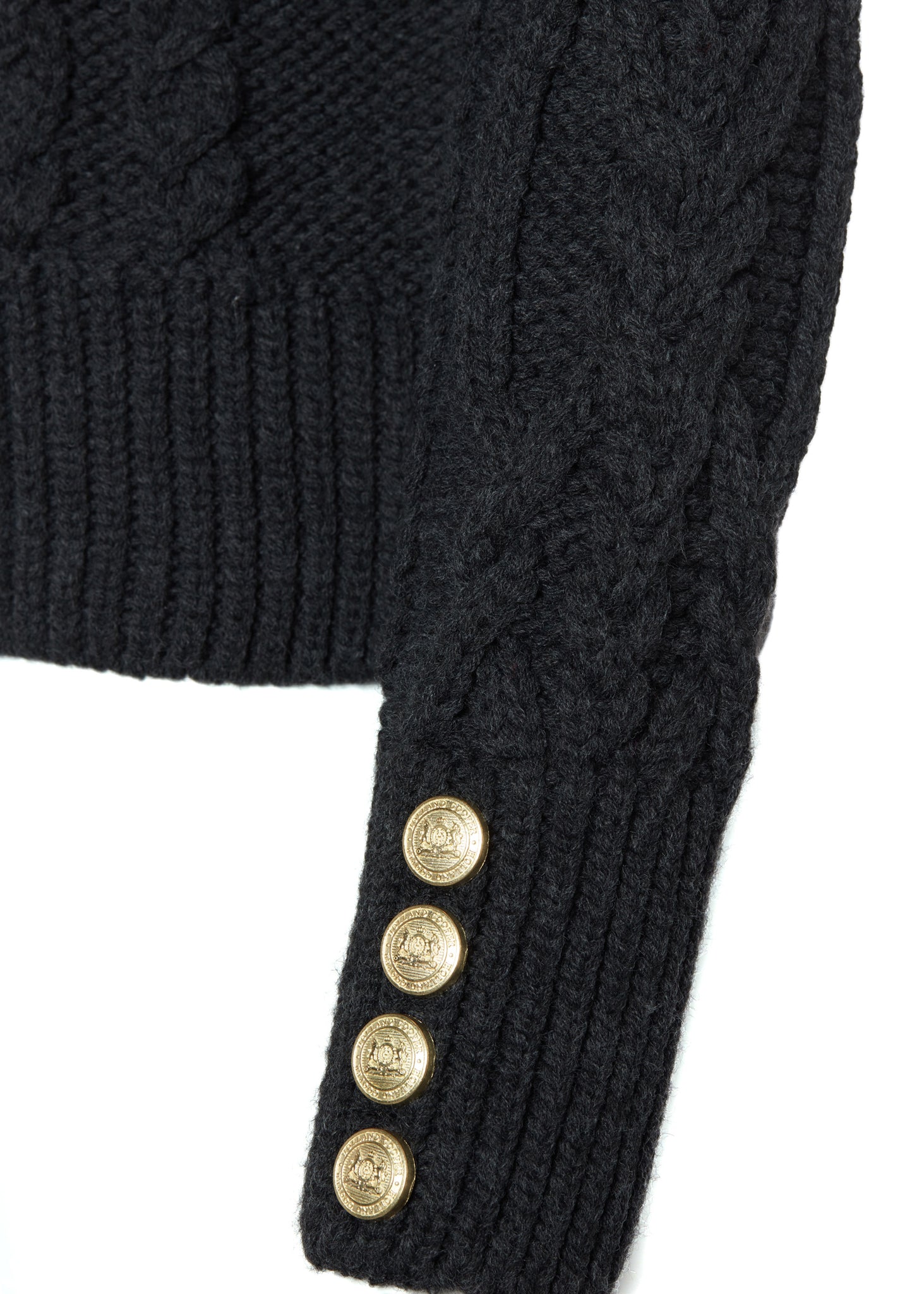 gold button detail on cuffs of a chunky cable knit roll neck jumper in dark grey with dropped shoulders and thick ribbed cable trims and gold buttons on cuffs and collar