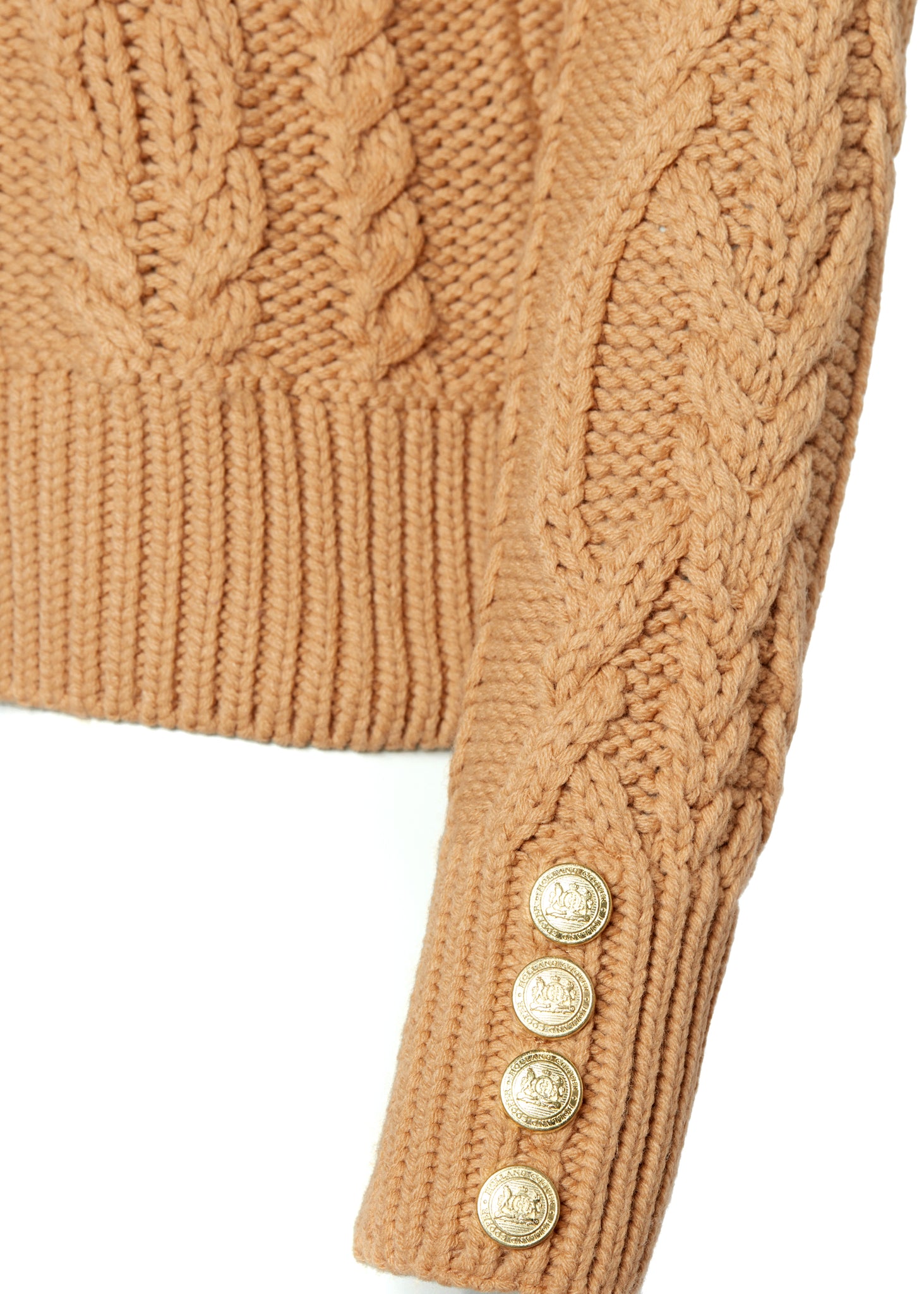 gold button detail on cuff of a chunky cable knit roll neck jumper in camel with dropped shoulders and thick ribbed cable trims and gold buttons on cuffs and collar