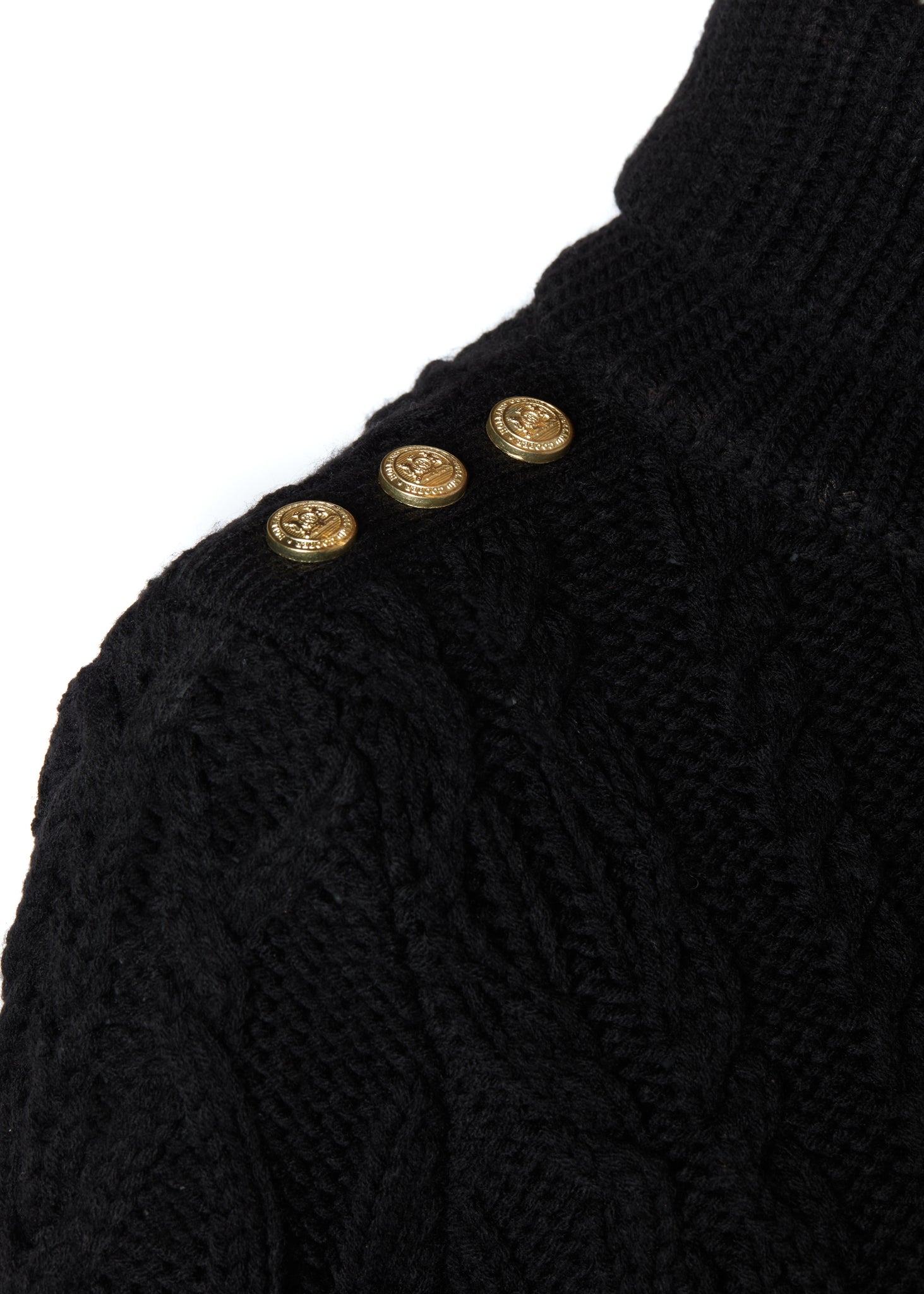 gold button detail across shoulders of a chunky cable knit roll neck jumper in black with dropped shoulders and thick ribbed cable trims and gold buttons on cuffs and collar
