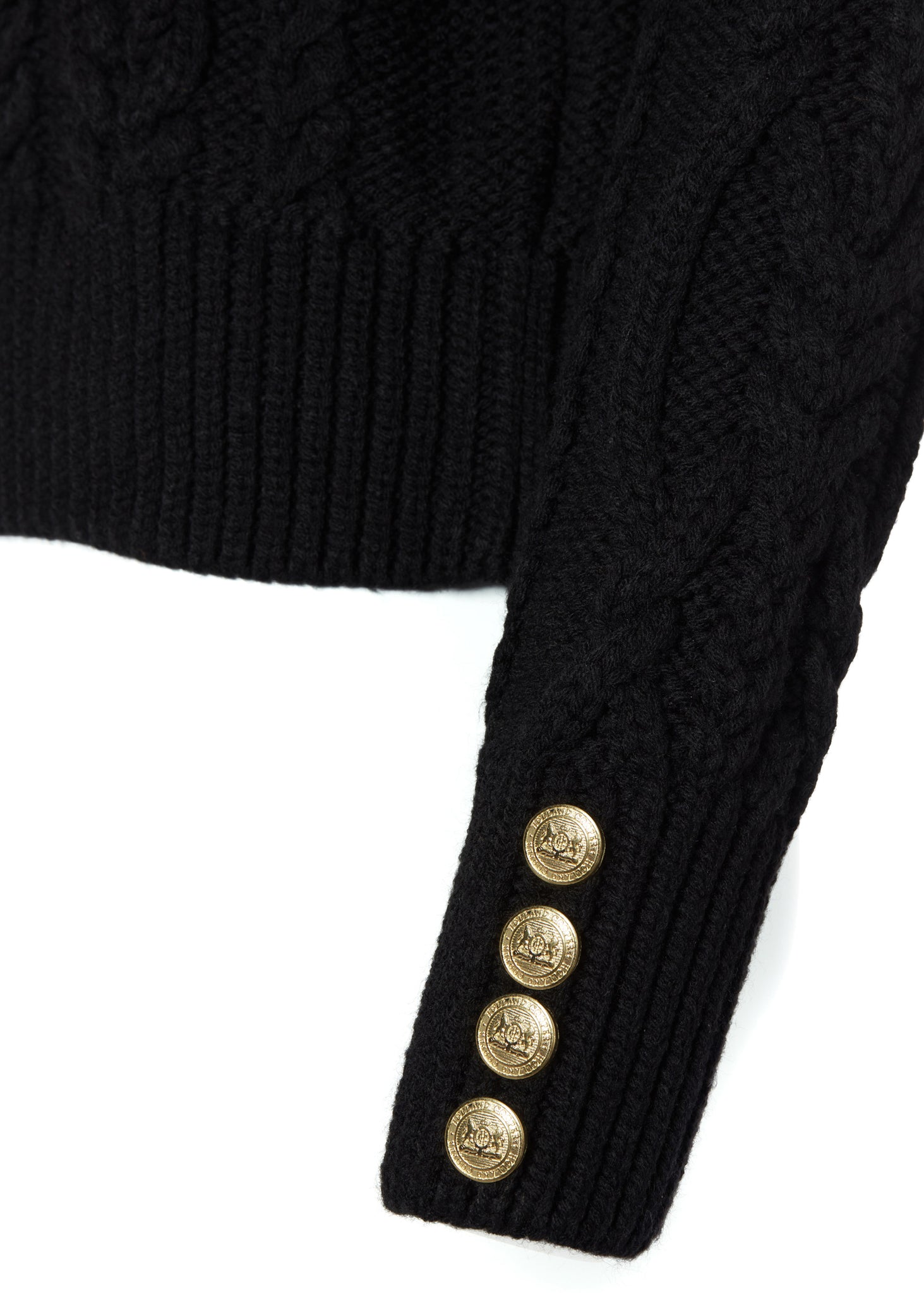 gold button detail on cuffs of a chunky cable knit roll neck jumper in black with dropped shoulders and thick ribbed cable trims and gold buttons on cuffs and collar