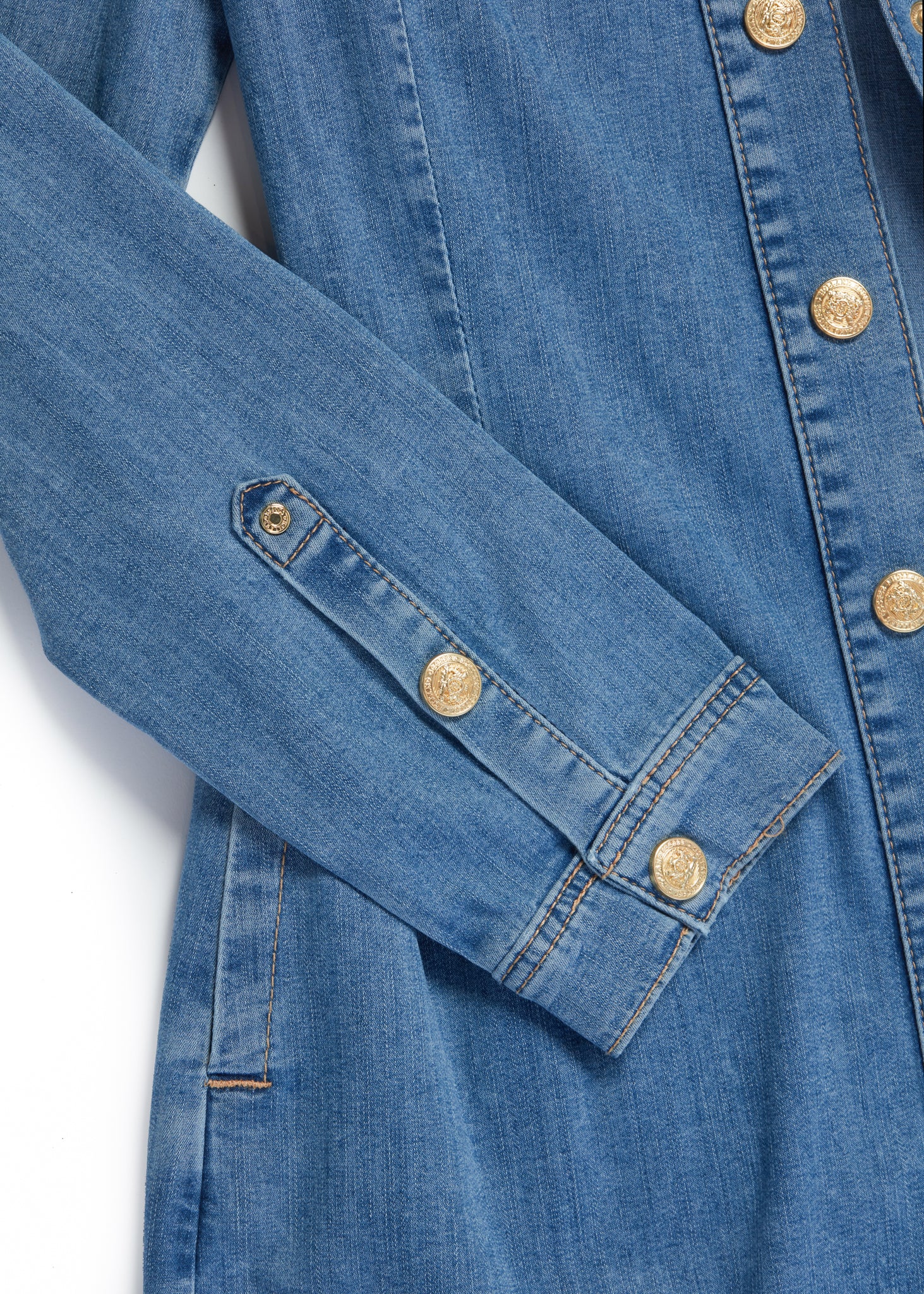 detail shot of gold buttons of womens long sleeve blue denim shirt mini dress